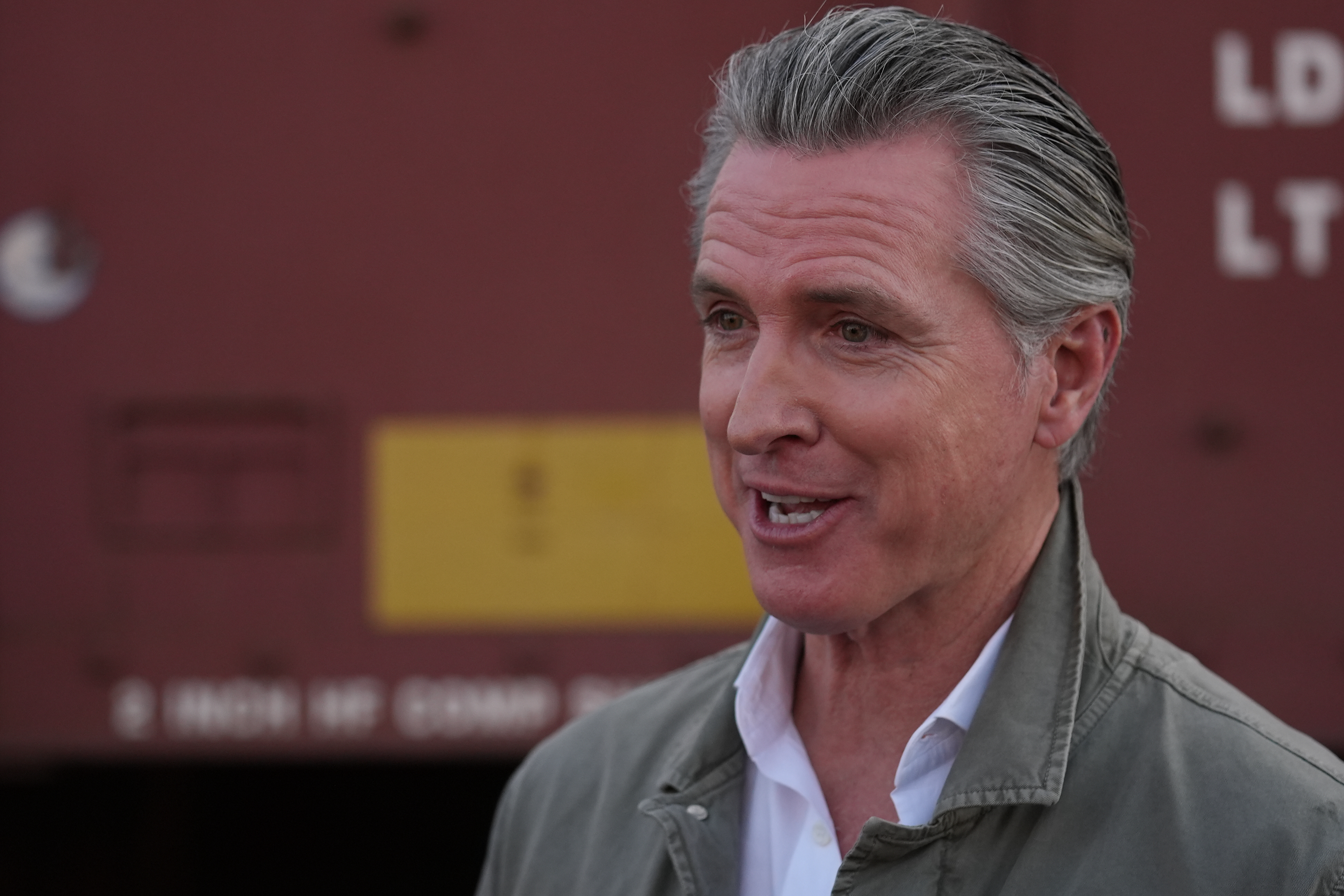 Gavin Newsom speaks to reporters at a news conference outdoors