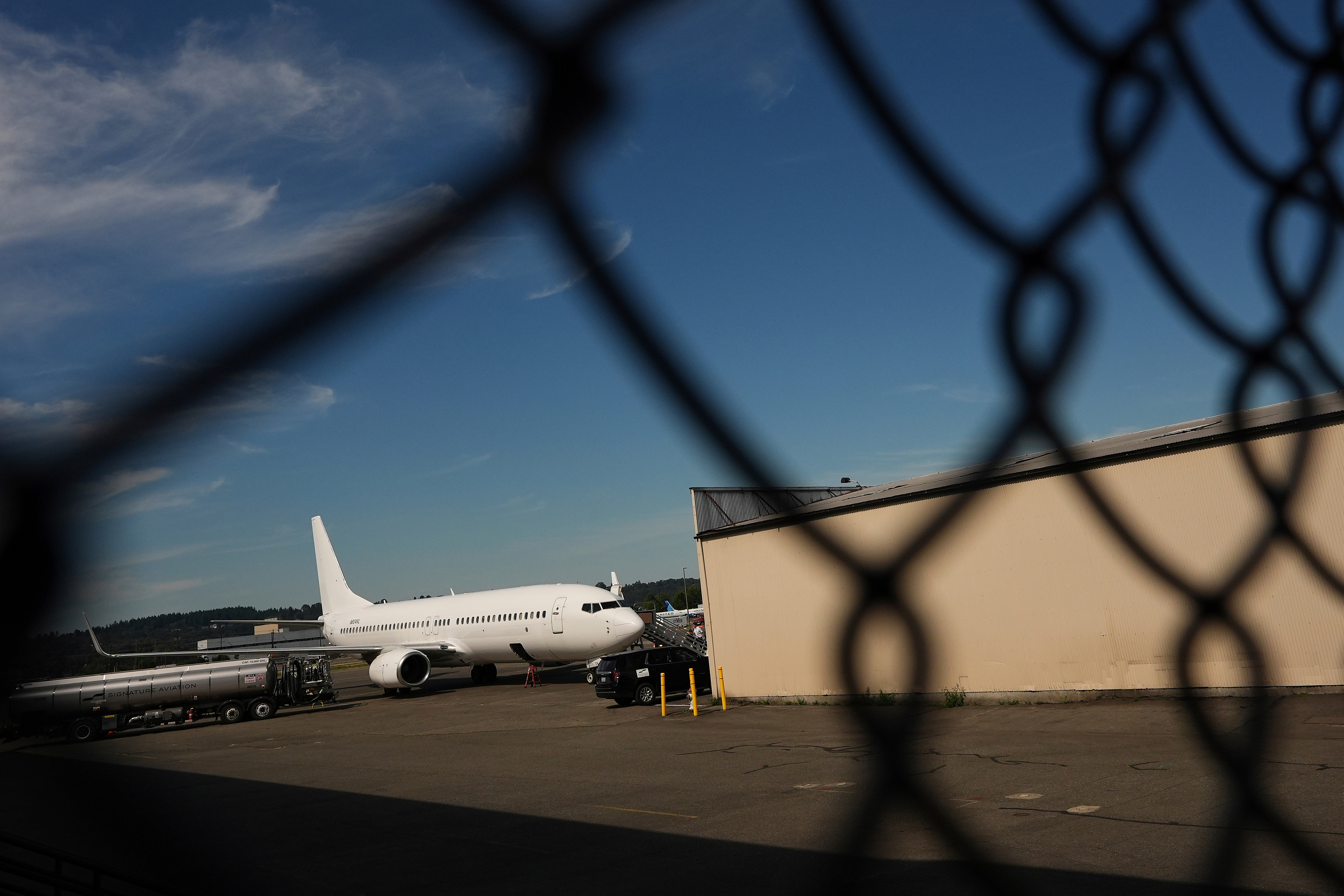 A deportation flight seen behind a chainlink fence.