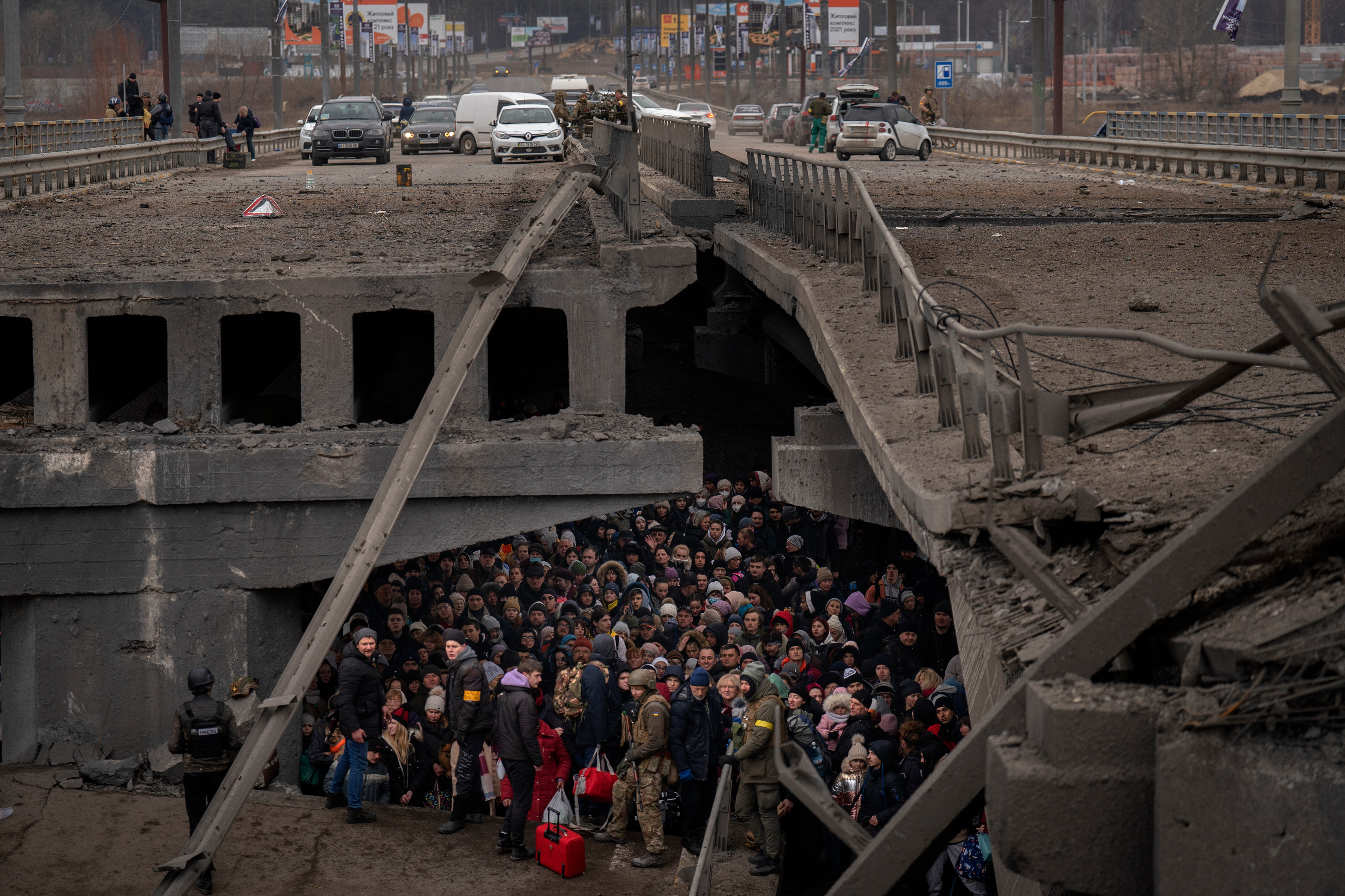 Ukrainians crowd under a destroyed bridge as they try to flee by crossing the Irpin River on the outskirts of Kyiv