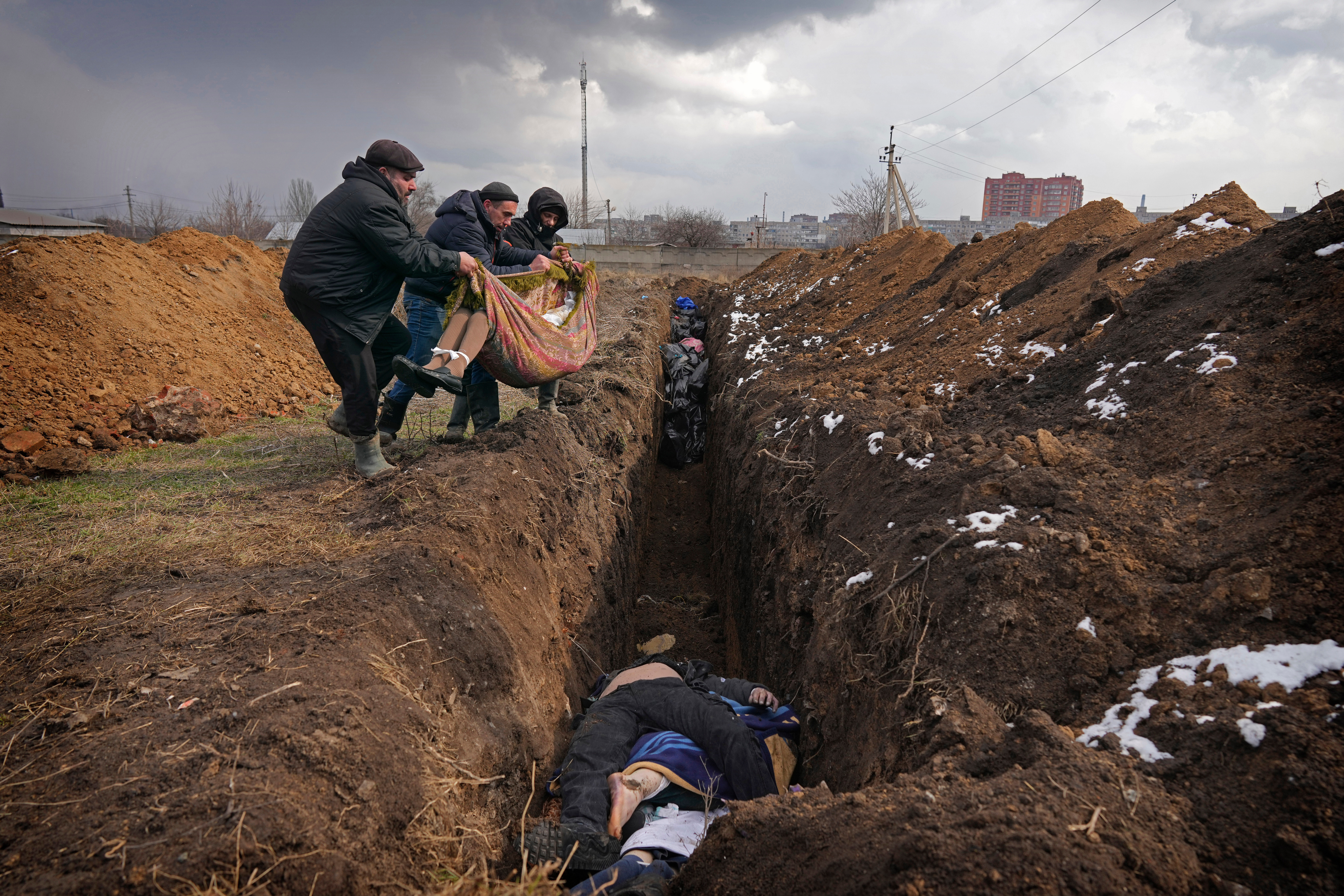 Bodies are placed into a mass grave on the outskirts of Mariupol, Ukraine