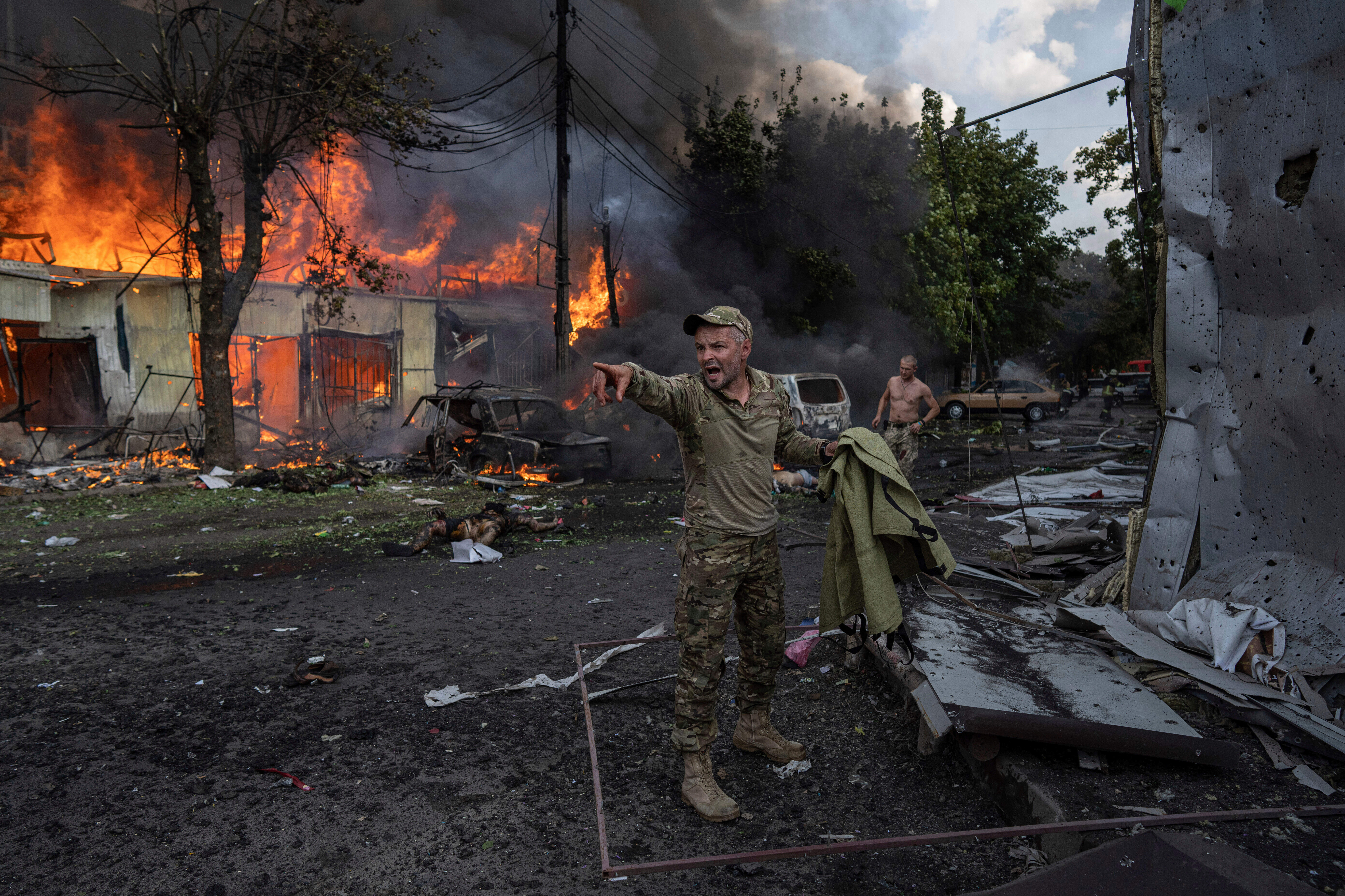 A Ukrainian serviceman shouts to paramedics in front of the bodies of people killed after a Russian rocket attack on the food market in the city centrer of Kostiantynivka, Ukraine