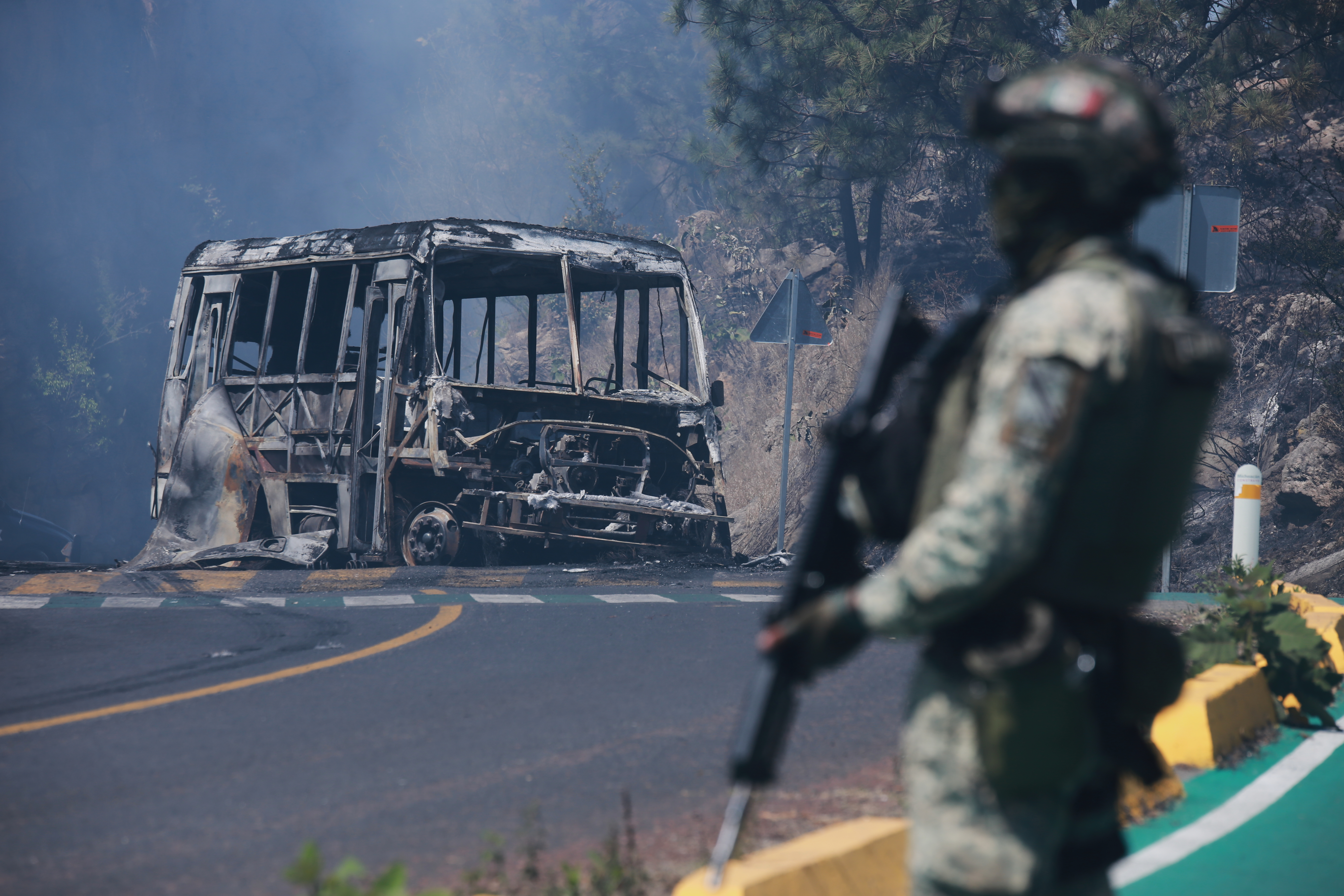 A soldier stands guard by a charred vehicle after it was set on fire, in Cointzio, Michoacán state, Mexico, Sunday, Feb. 22, 2026, following the death of the leader of the Jalisco New Generation Cartel, Nemesio Oseguera, known as "El Mencho." (AP Photo/Armando Solis)