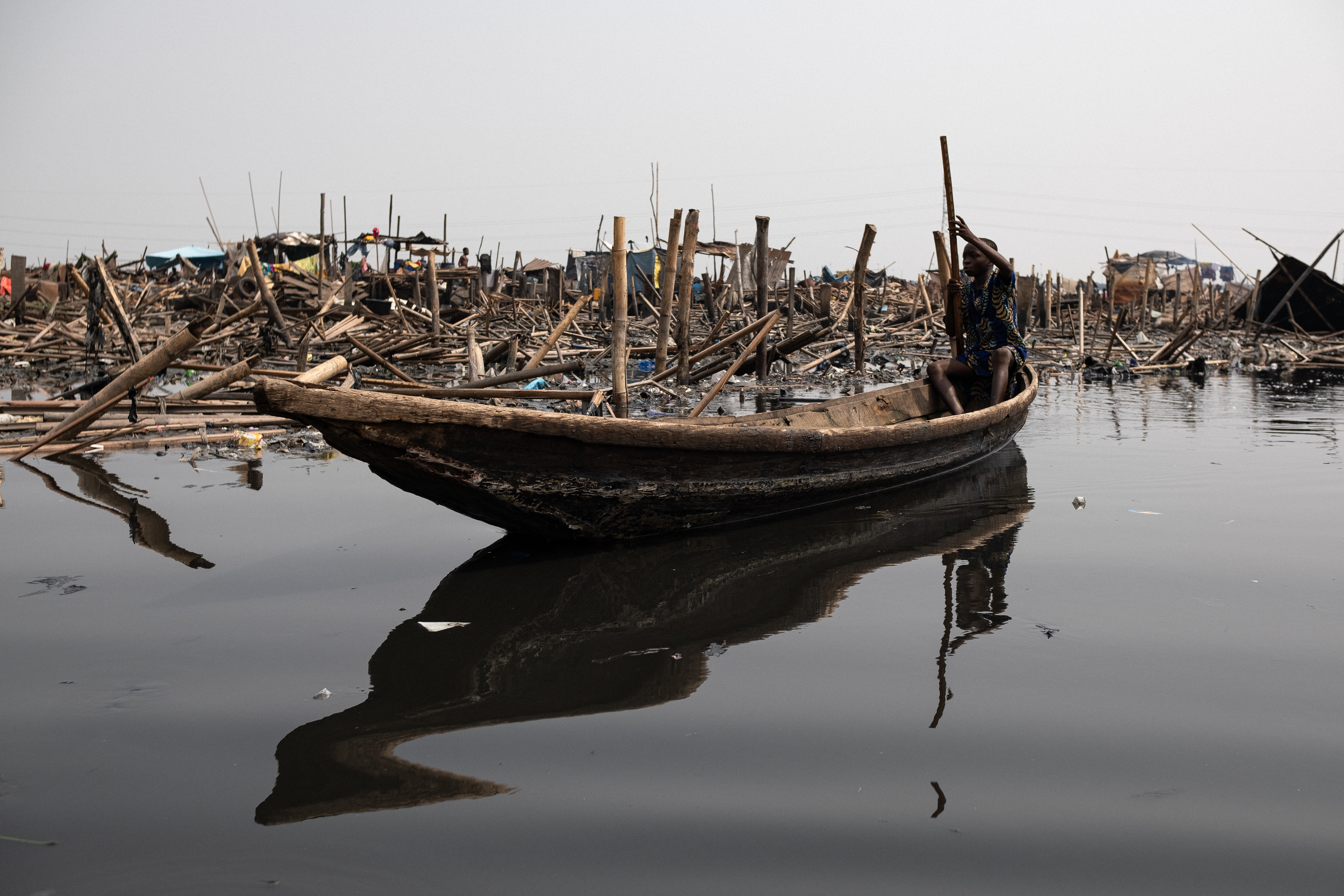 A boy paddles past the ruins after demolitions.