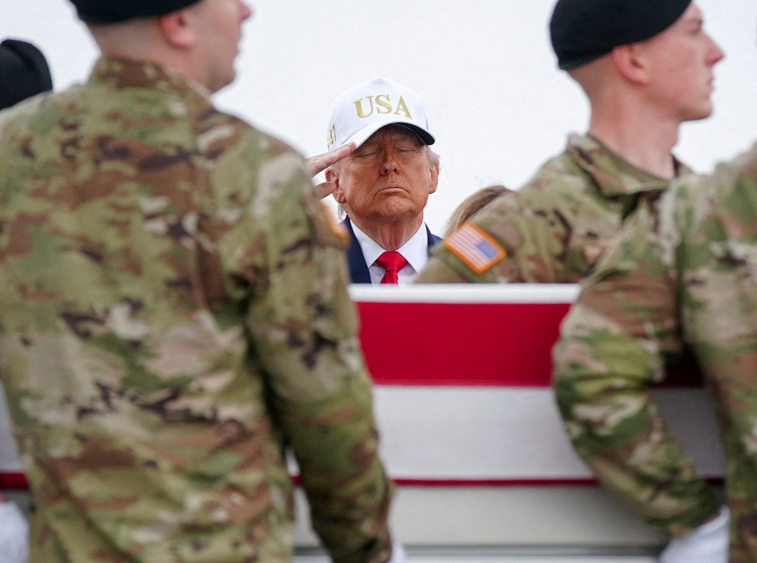 U.S. President Donald Trump salutes as members of the military carry a transfer case during a dignified transfer of the remains of six U.S. Army service members who were killed in Kuwait. [Nathan Howard/Reuters]