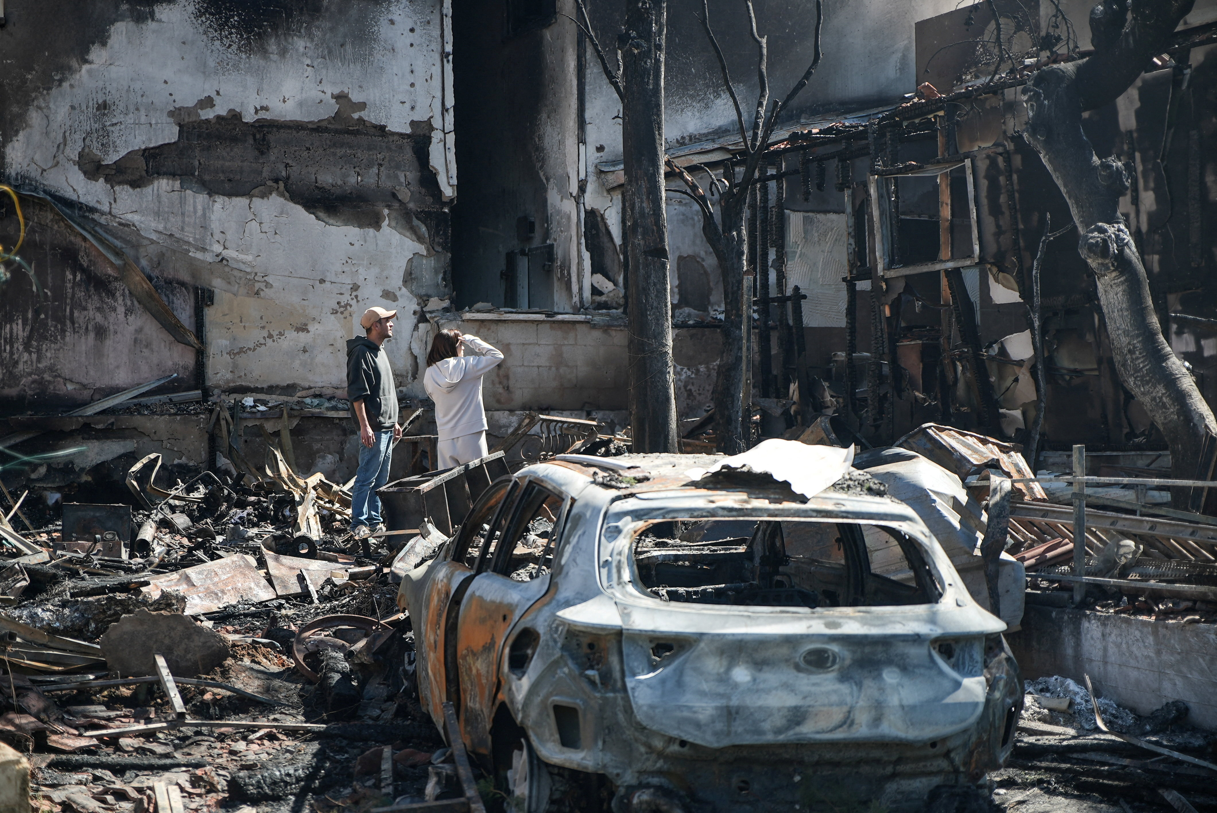 Neighbours look at the remains of Haim Azikry's home that was burned following a Hezbollah rocket attack, amid escalation between Hezbollah and Israel, and amid the U.S.-Israeli conflict with Iran, in Nahariya, northern Israel, March 17, 2026.