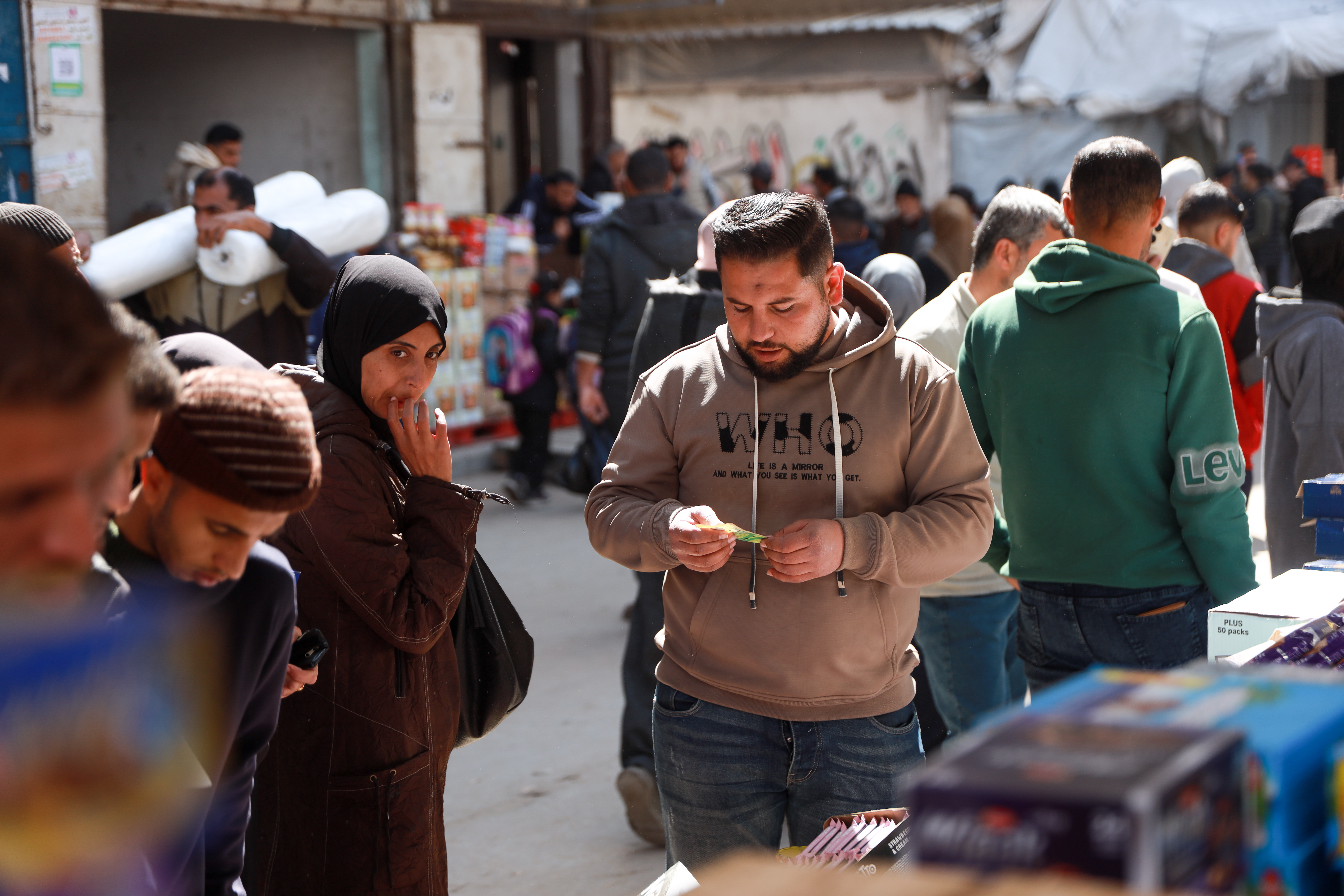 Omar Al-Ghazali sells groceries from his food stall in Nuseirat market in central Gaza [Abdelhakim Abu Riash/ Al Jazeera] 