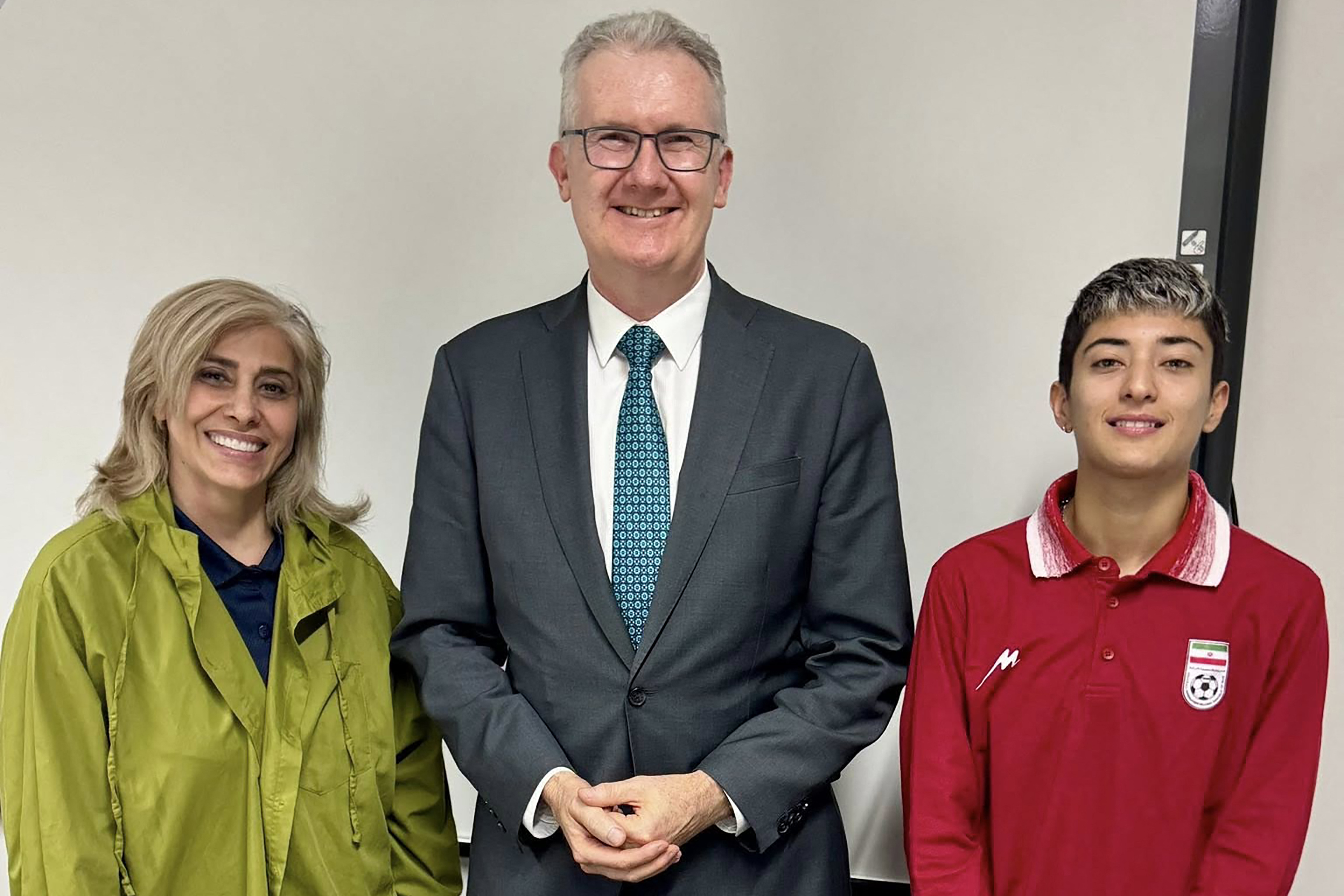 Australia's Home Affairs Minister Tony Burke (C) with Iranian women's football team player Mohaddeseh Zolfi (R) and support member Zahra Soltan Meshkeh Kar (L)