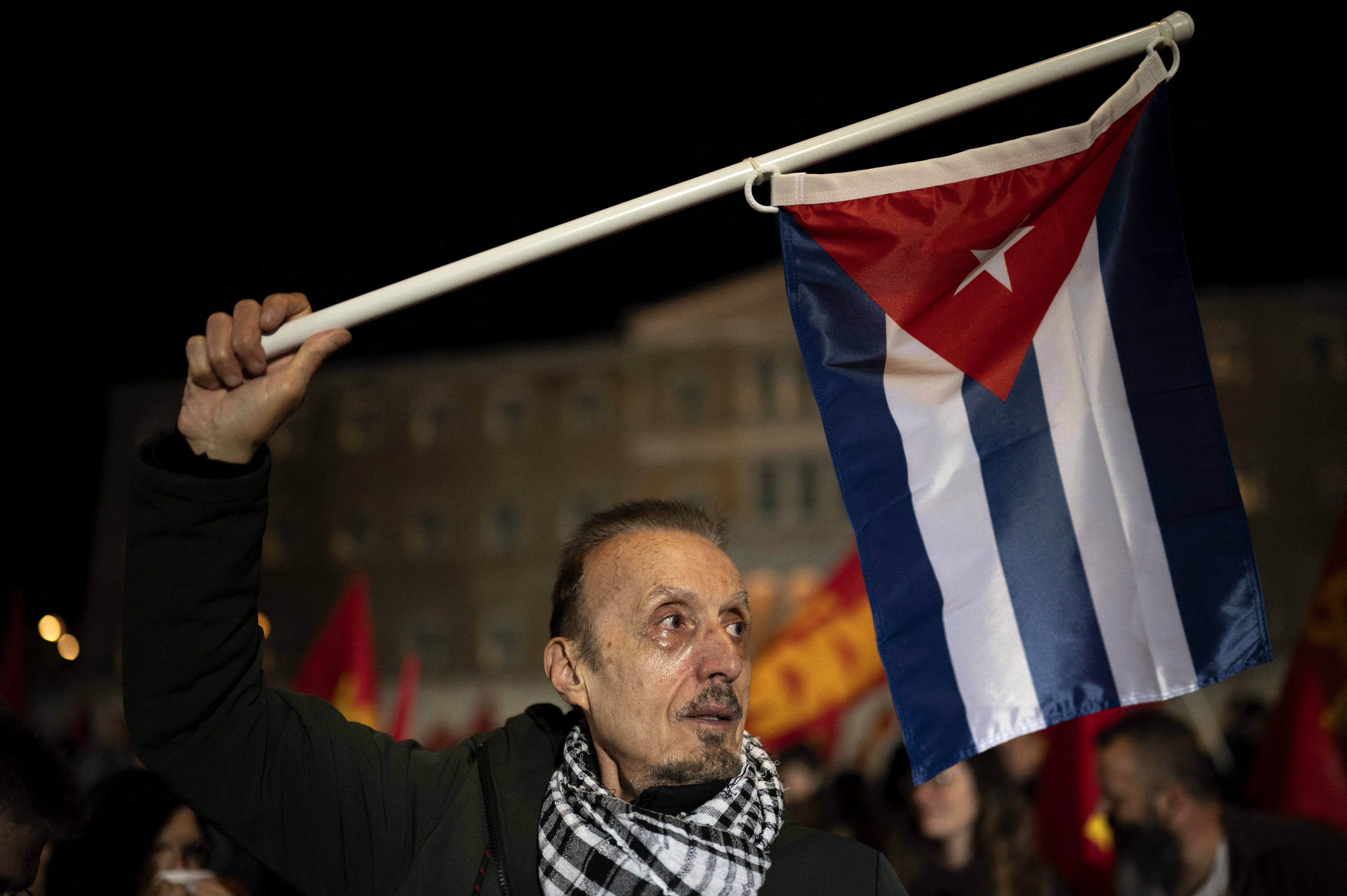 A supporter of the Greek Communist Party KKE holds a flag of Cuba during a demonstration against the economic suffocation and the aggression plans announced by US President Donald Trump, outside the Greek parliament in Athens on March 11, 2026. [Aggelos Nakkas/ Reuters]