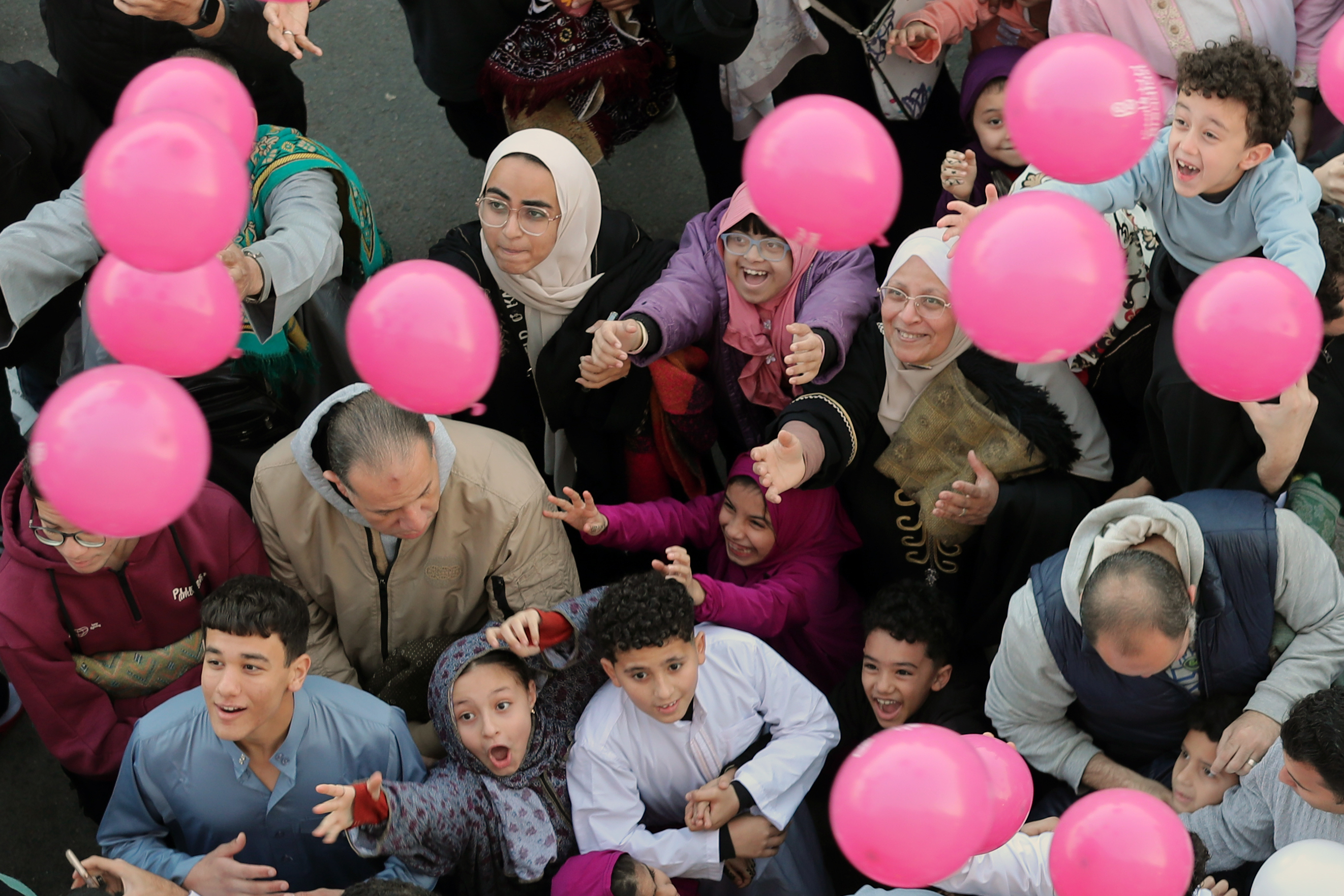 People try to catch free balloons distributed during Eid al-Fitr, marking the end of the Muslim holy fasting month of Ramadan, outside al-Seddik mosque in Cairo, Egypt,, Friday, March 20, 2026. (AP Photo/Khaled el Fiqi)
