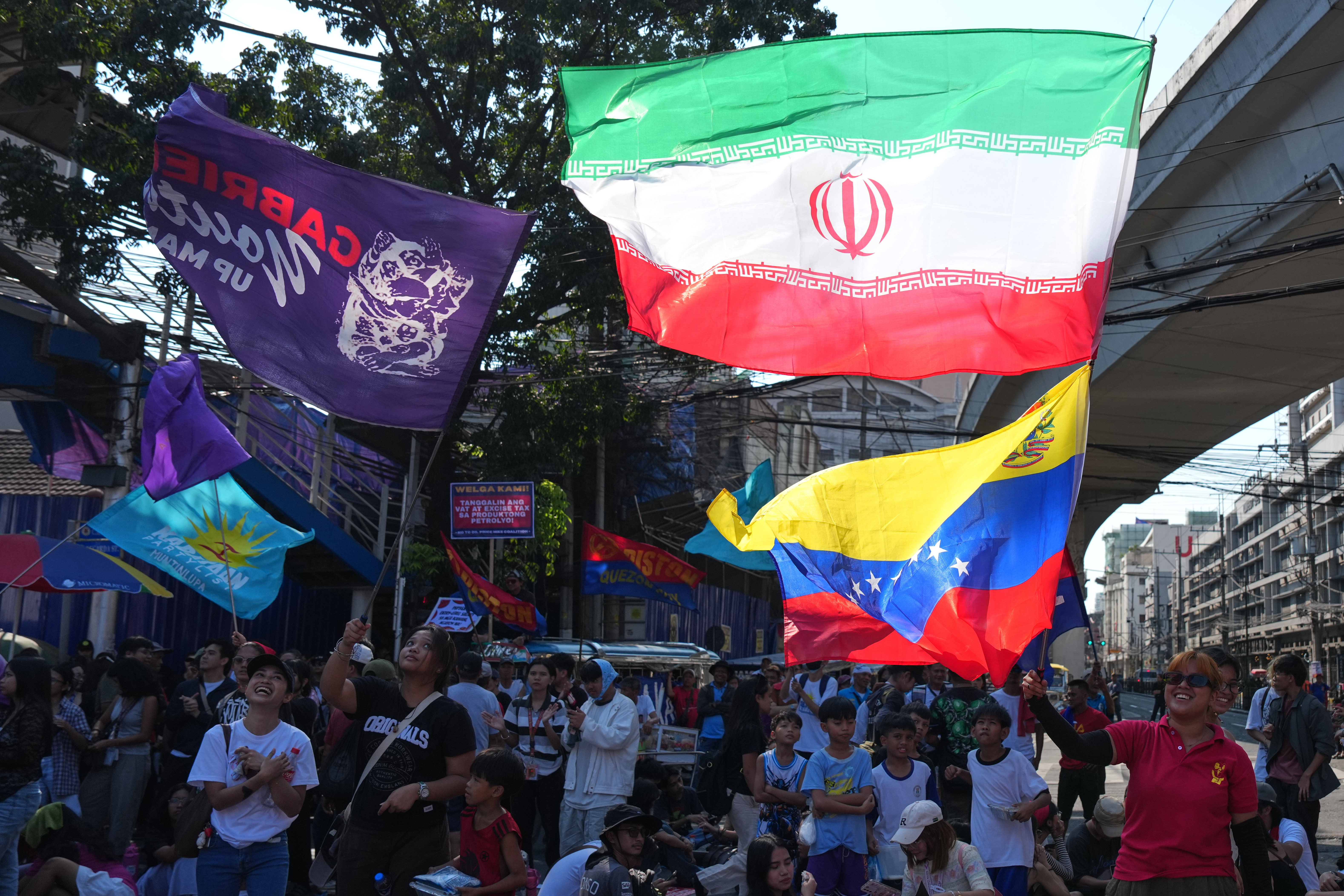 Protesters wave an Iranian flag during a rally by transport workers and activists protesting the rise in oil prices on Friday, March 27, 2026, near the Malacanang presidential palace in Manila, Philippines. (AP Photo/Aaron Favila)