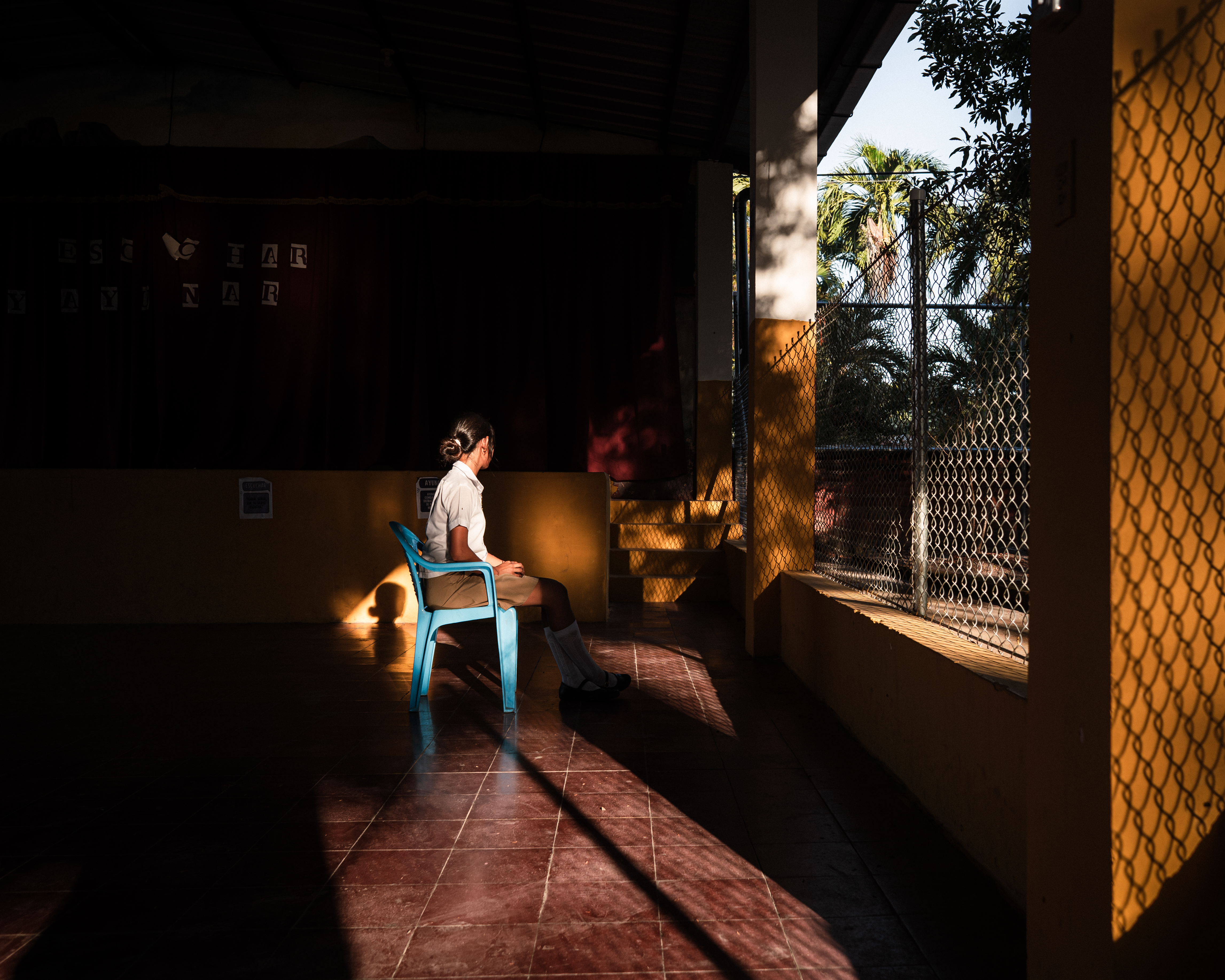 Sara’s de Perez granddaughter, 16, in the courtyard of the church of El Rosario, El Salvador, wearing her school uniform. [Euan Wallace/ Al Jazeera]