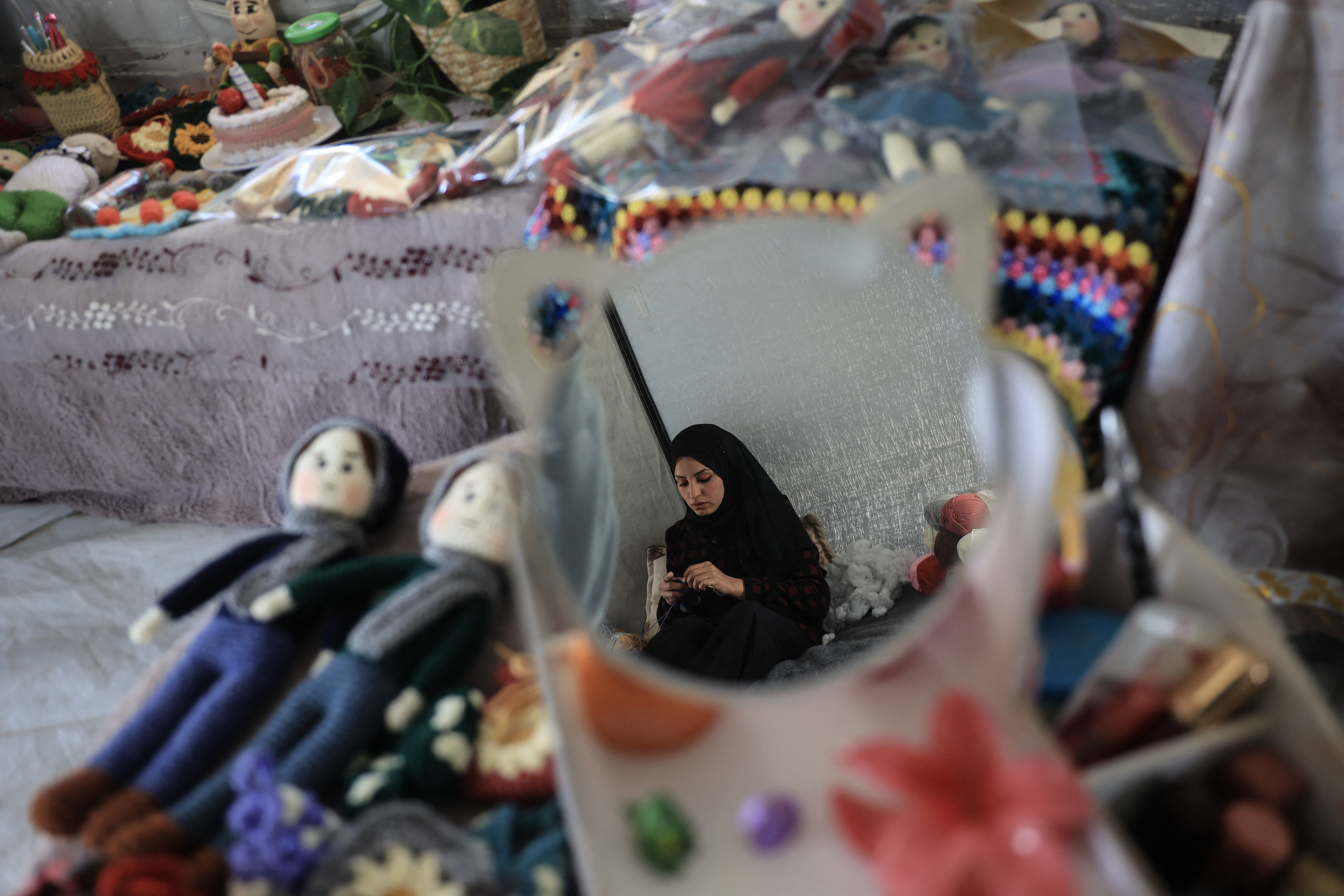 Displaced Palestinian Shireen al-Kurdi makes crochet dolls to sell for the Eid al-Fitr holiday, which marks the end of the Muslim holy month of Ramadan, at the Bureij refugee camp in the central Gaza Strip on March 17, 2026.
