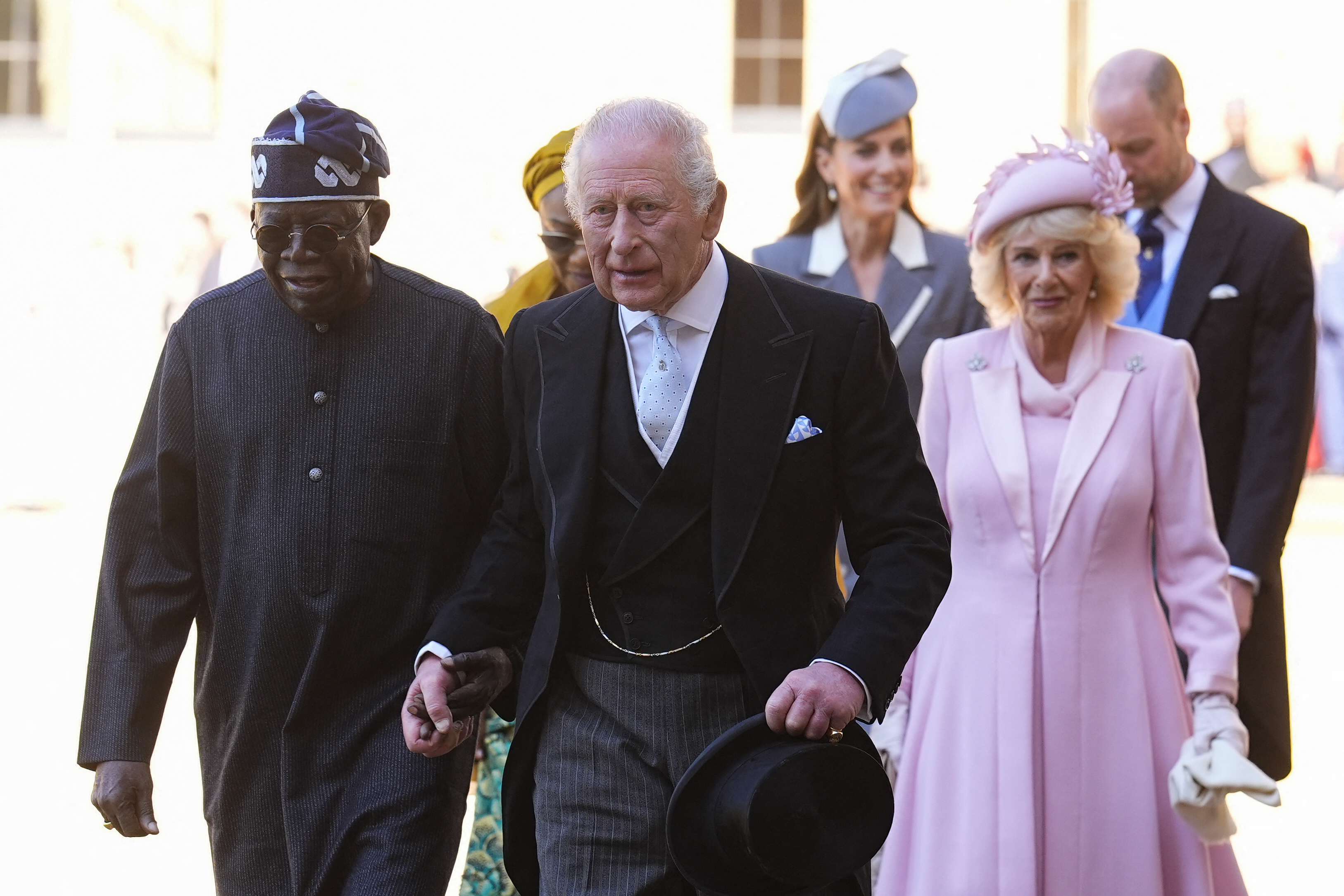 Britain's King Charles III and Nigeria's President Bola Tinubu hold hands as they leave, followed by Nigeria's First Lady Oluremi Tinubu and Britain's Queen Camilla, and Britain's Catherine, Princess of Wales and Britain's Prince William, Prince of Wales, following a ceremonial welcome in the Quadrangle at Windsor Castle, in Windsor, on March 18, 2026, on the first day of a two-day State Visit to the United Kingdom by Nigeria's President. (Photo by Aaron Chown / POOL / AFP)