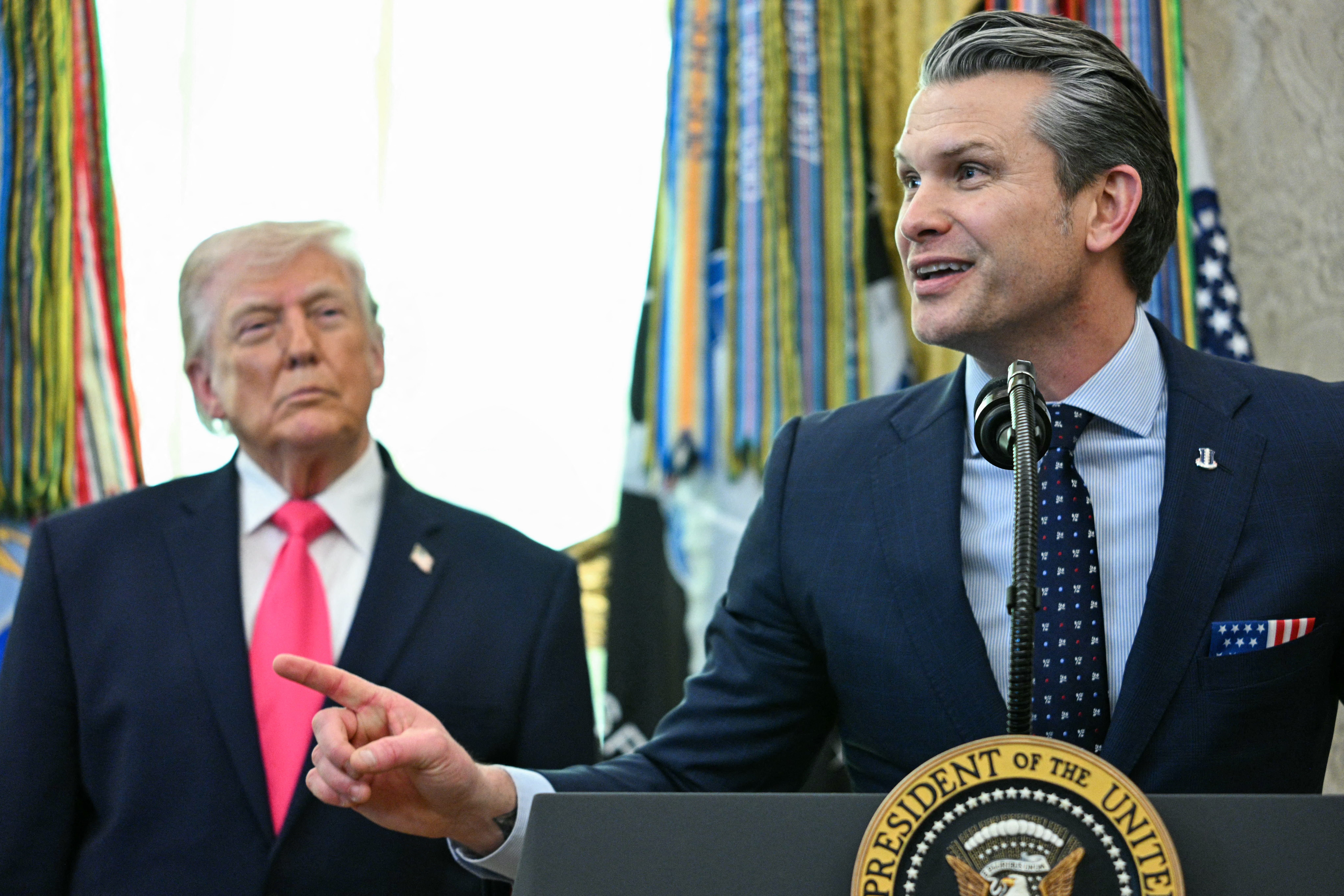 (L/R) US President Donald Trump looks on as Secretary of Defense Pete Hegseth speaks during a swearing in ceremony for new Homeland Security Secretary Markwayne Mullin in the Oval Office of the White House in Washington, DC, on March 24, 2026.