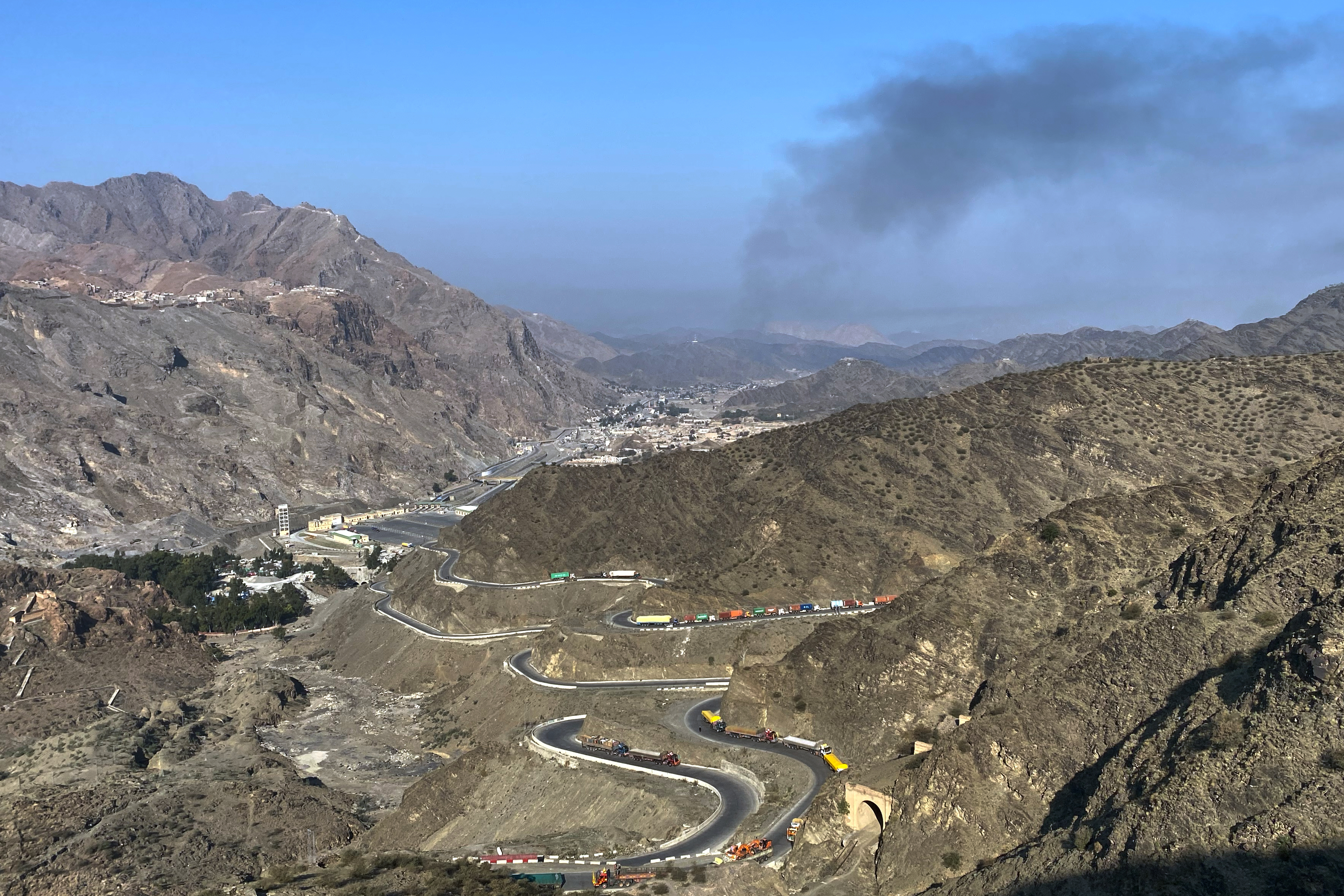 Smoke emits from the Afghan side as trucks are parked along the roadside following cross-border clashes between Pakistan and Afghan forces near the Torkham border crossing point, Pakistan on February 28, 2026.