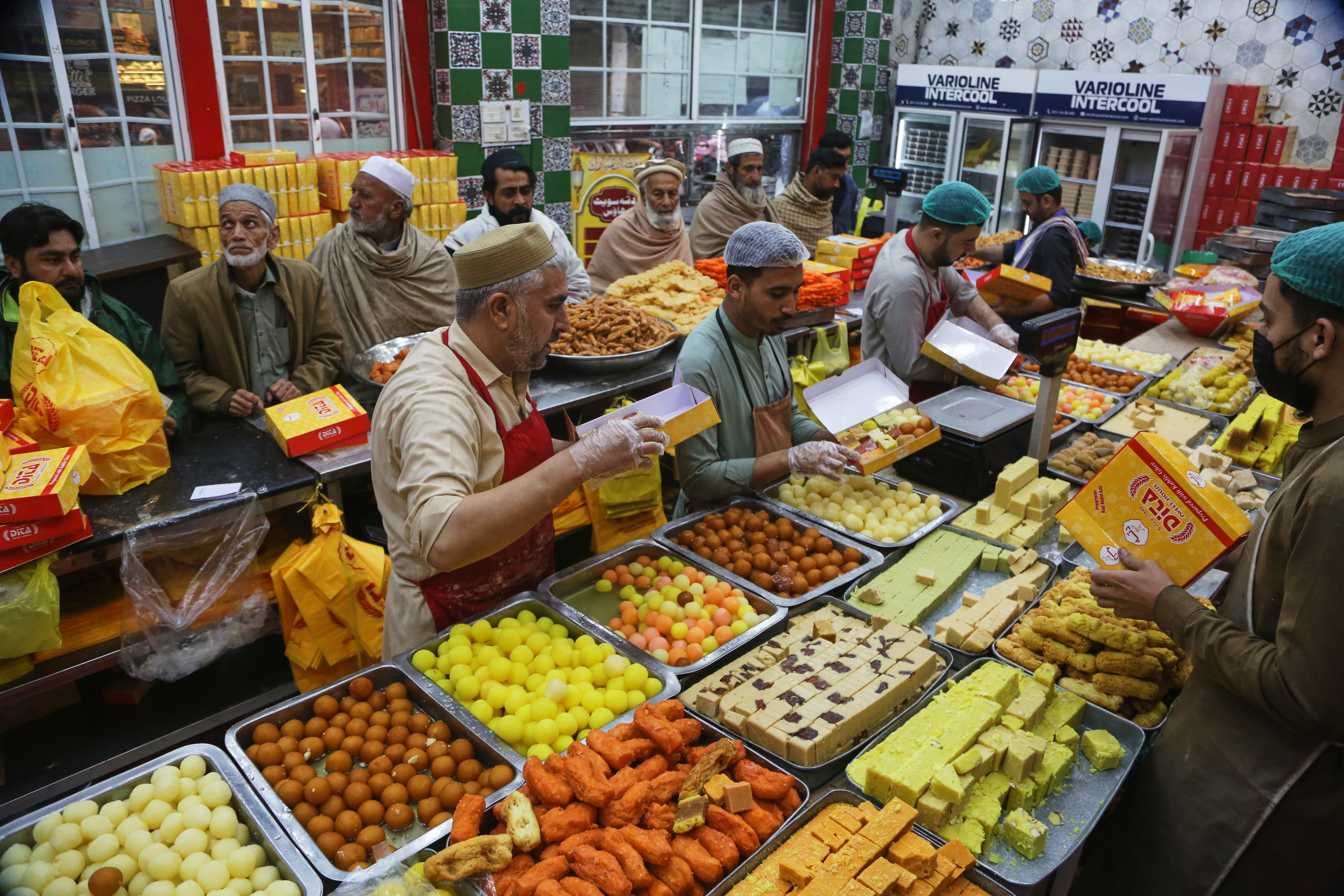 People buy traditional sweets at a shop in preparation for the upcoming Eid al-Fitr celebrations, which marks the end of the Islamic holy month of Ramadan in Peshawar, Pakistan, Wednesday, March 18, 2026. (AP Photo/Muhammad Sajjad)
