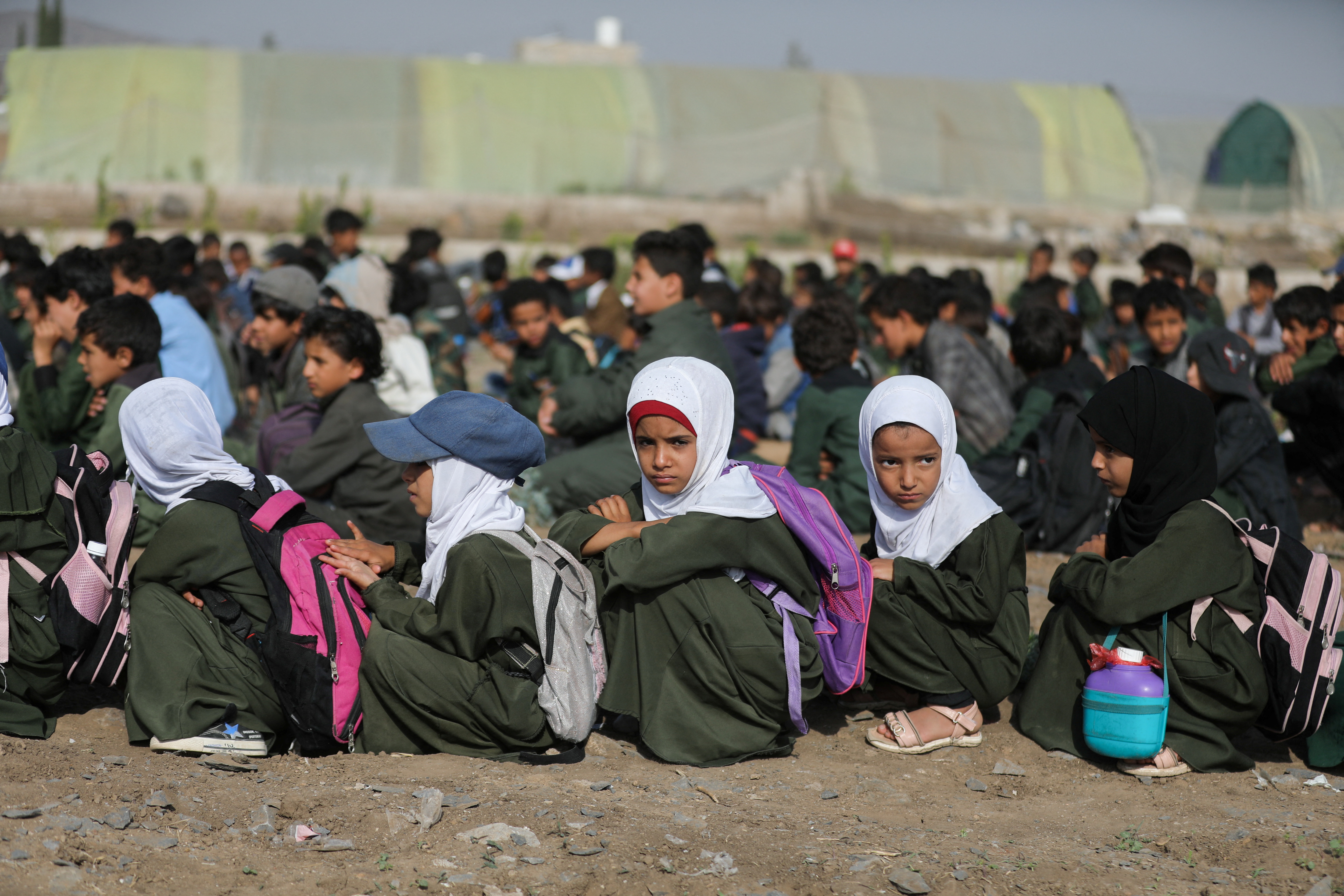 Students use paper sheets to shelter from the sun