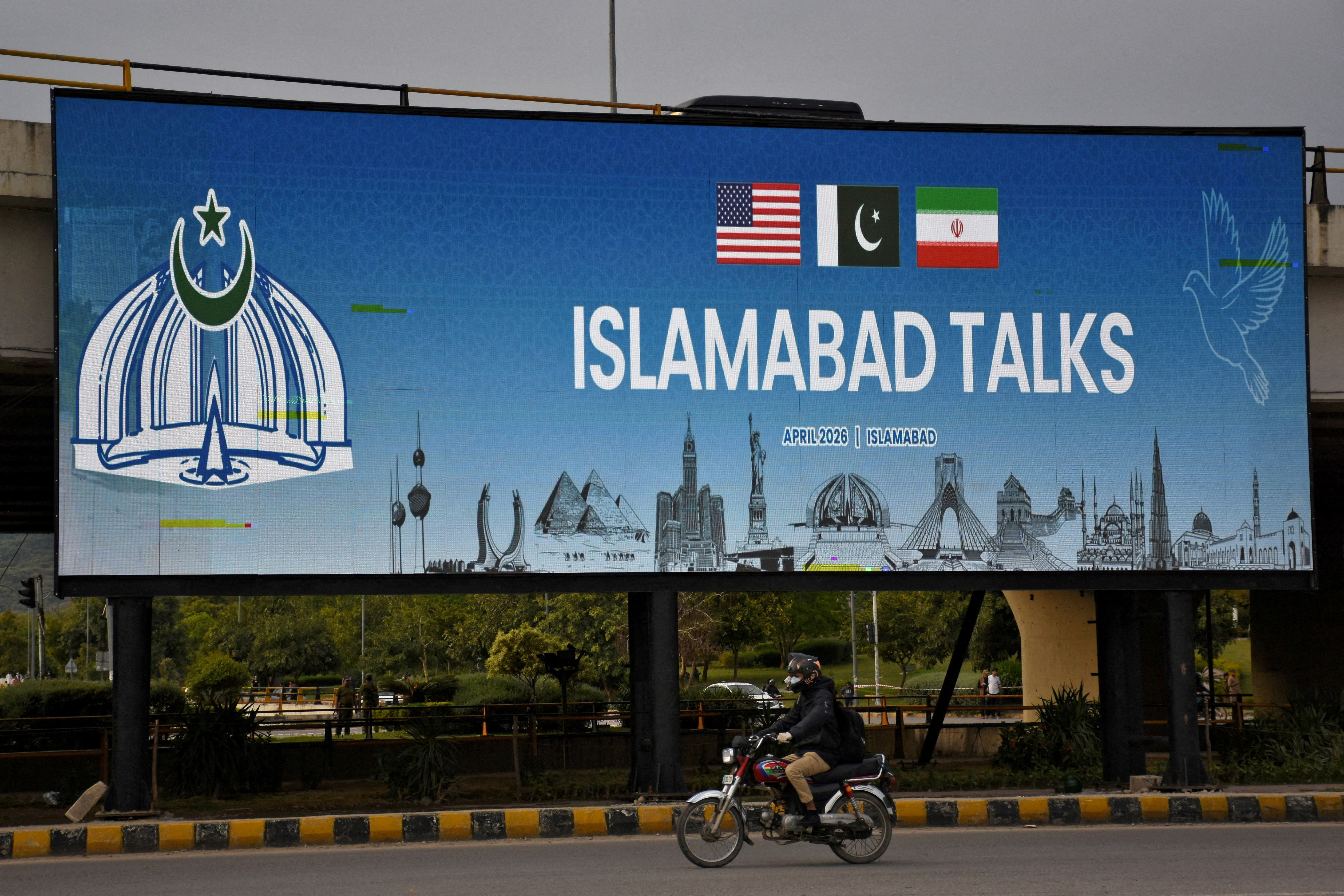 A man rides his motorbike past a billboard installed alongside a road as Pakistan prepares to host the U.S. and Iran for peace talks, in Islamabad, Pakistan, April 10, 2026. REUTERS/Waseem Khan REFILE - REMOVING EXTRA WORDS "AT THE BARBER SHOP". TPX IMAGES OF THE DAY