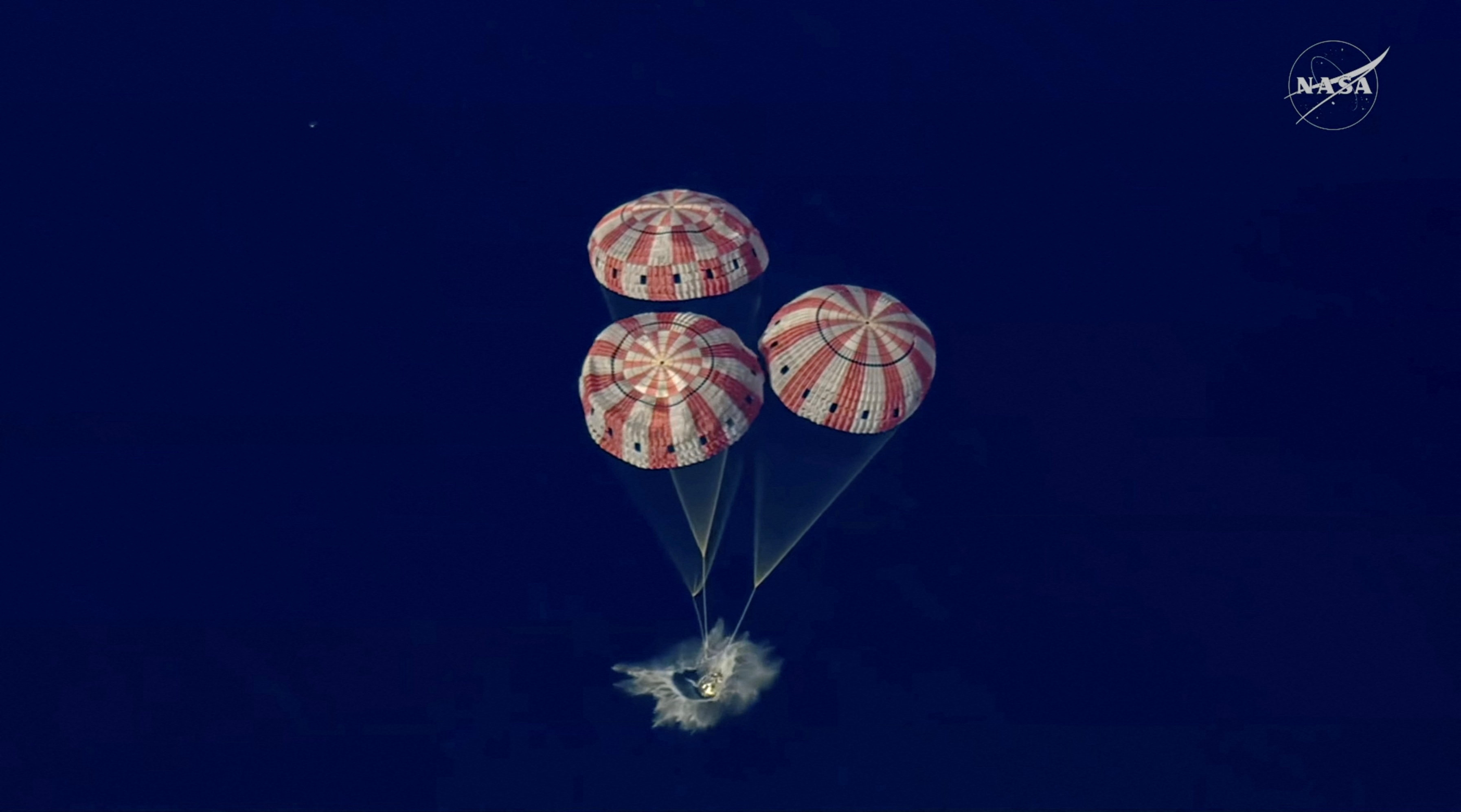 The Artemis II crew capsule splashes down in the Pacific Ocean in this screengrab from a livestream video after the Artemis II crew's flyby of the Moon