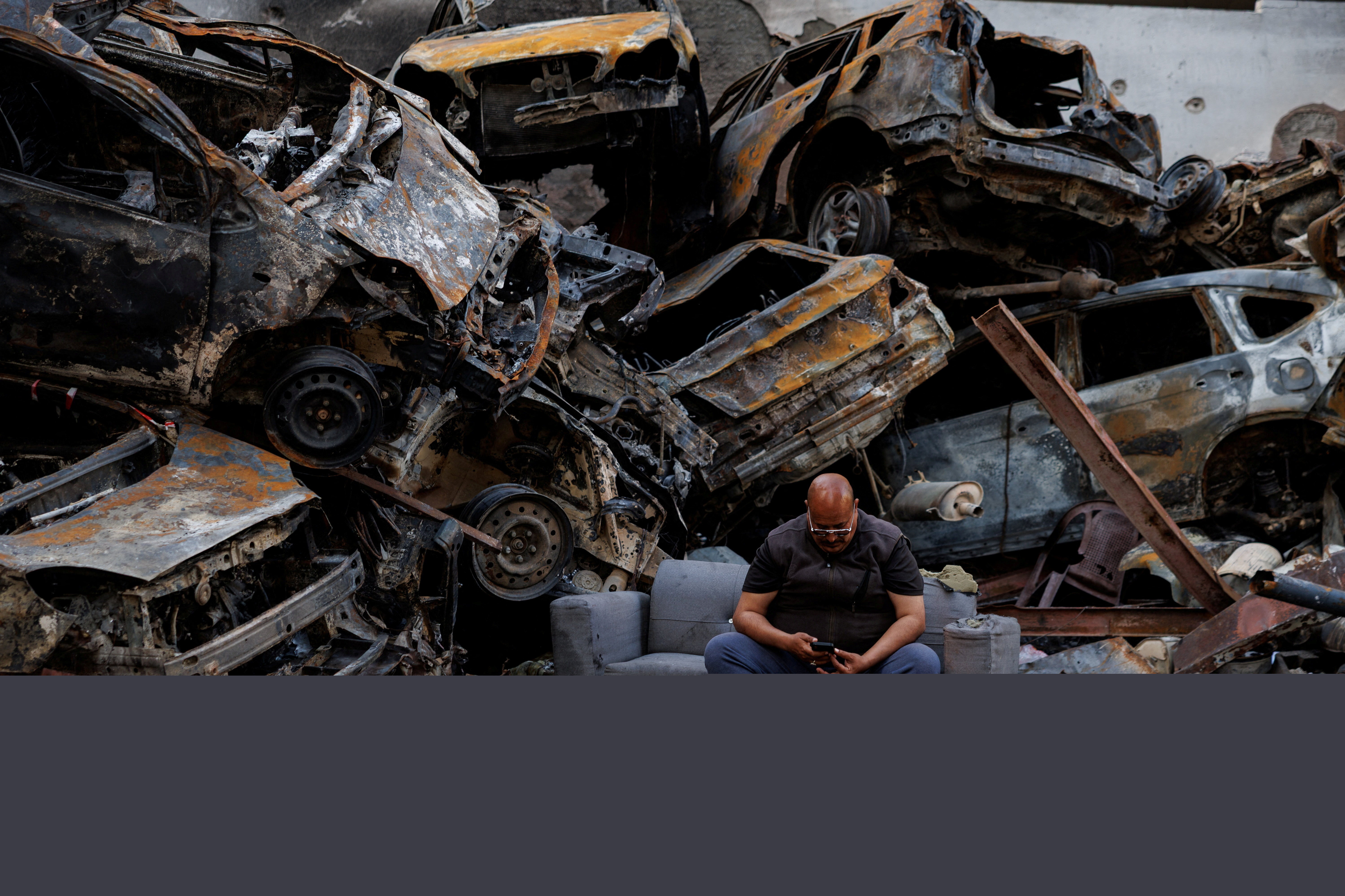 Mohamed El Junayd, 43, who said he survived the Israeli strike, sits beside piled damaged cars at the site of an Israeli strike carried out on April 8, at Corniche al-Mazraa in Beirut, Lebanon April 13, 2026.