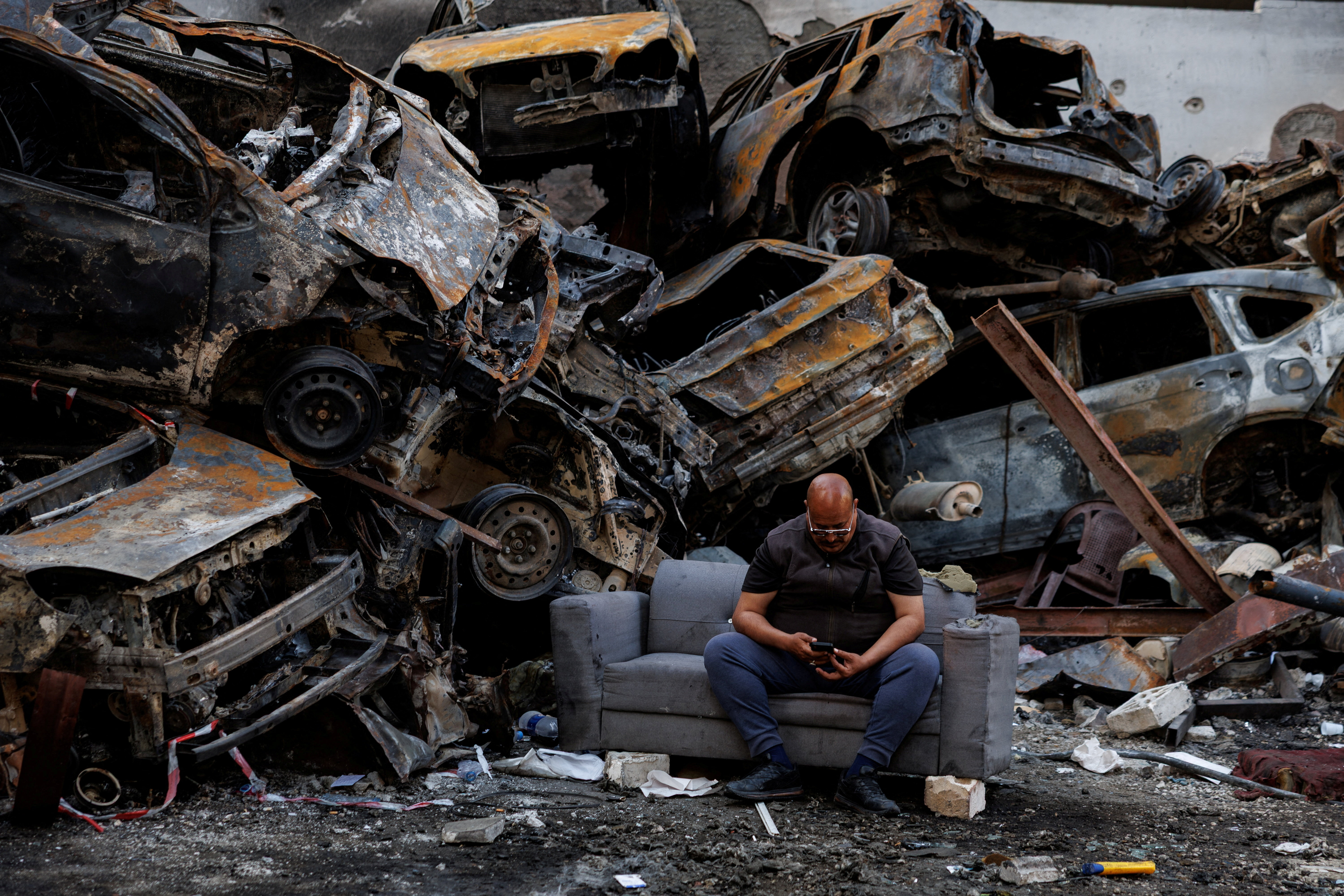 Mohamed El Junayd, 43, who said he survived the Israeli strike, sits beside piled damaged cars at the site of an Israeli strike carried out on April 8, at Corniche al-Mazraa in Beirut, Lebanon April 13, 2026.