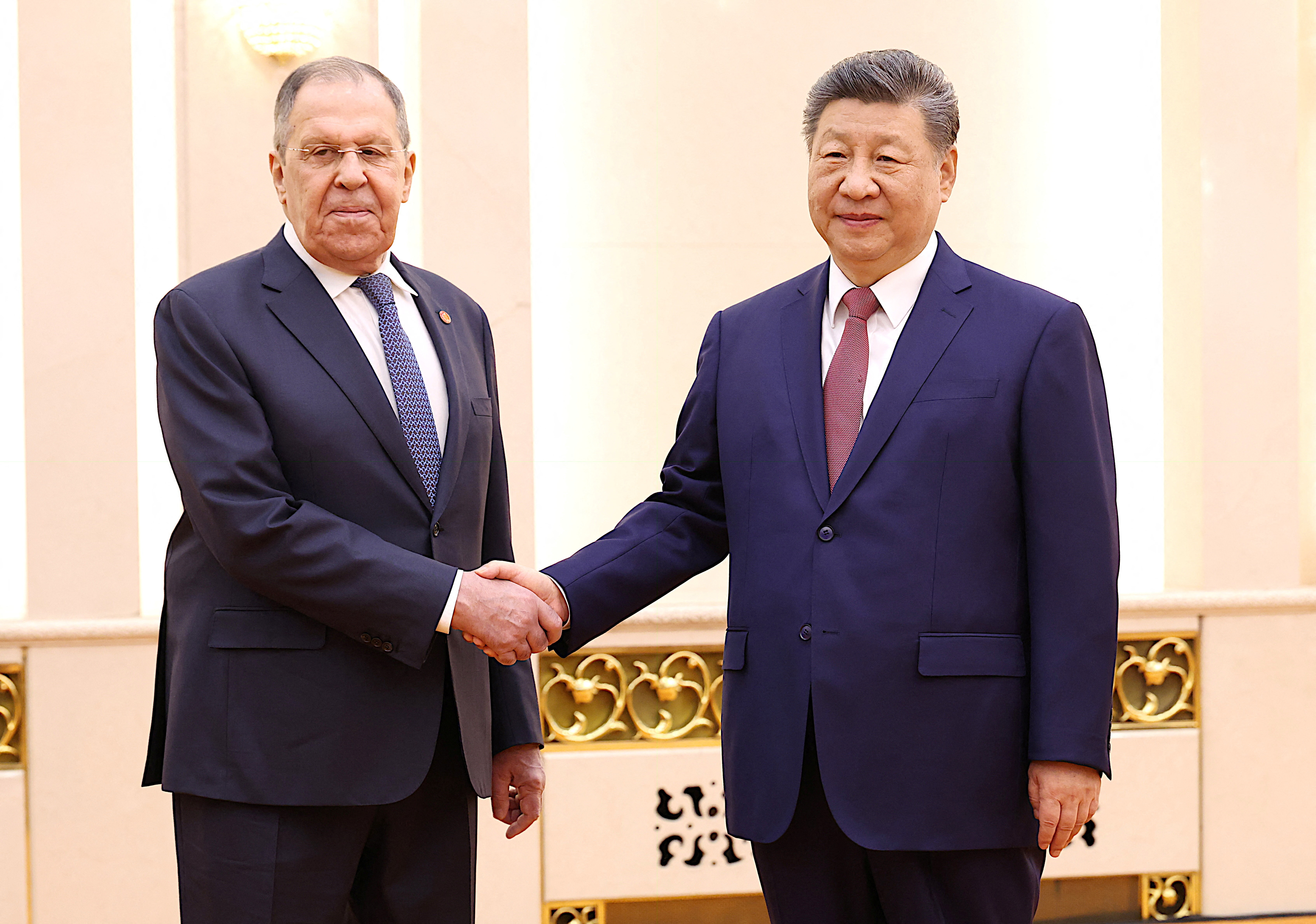 Chinese President Xi Jinping and Russia's Foreign Minister Sergey Lavrov shake hands.