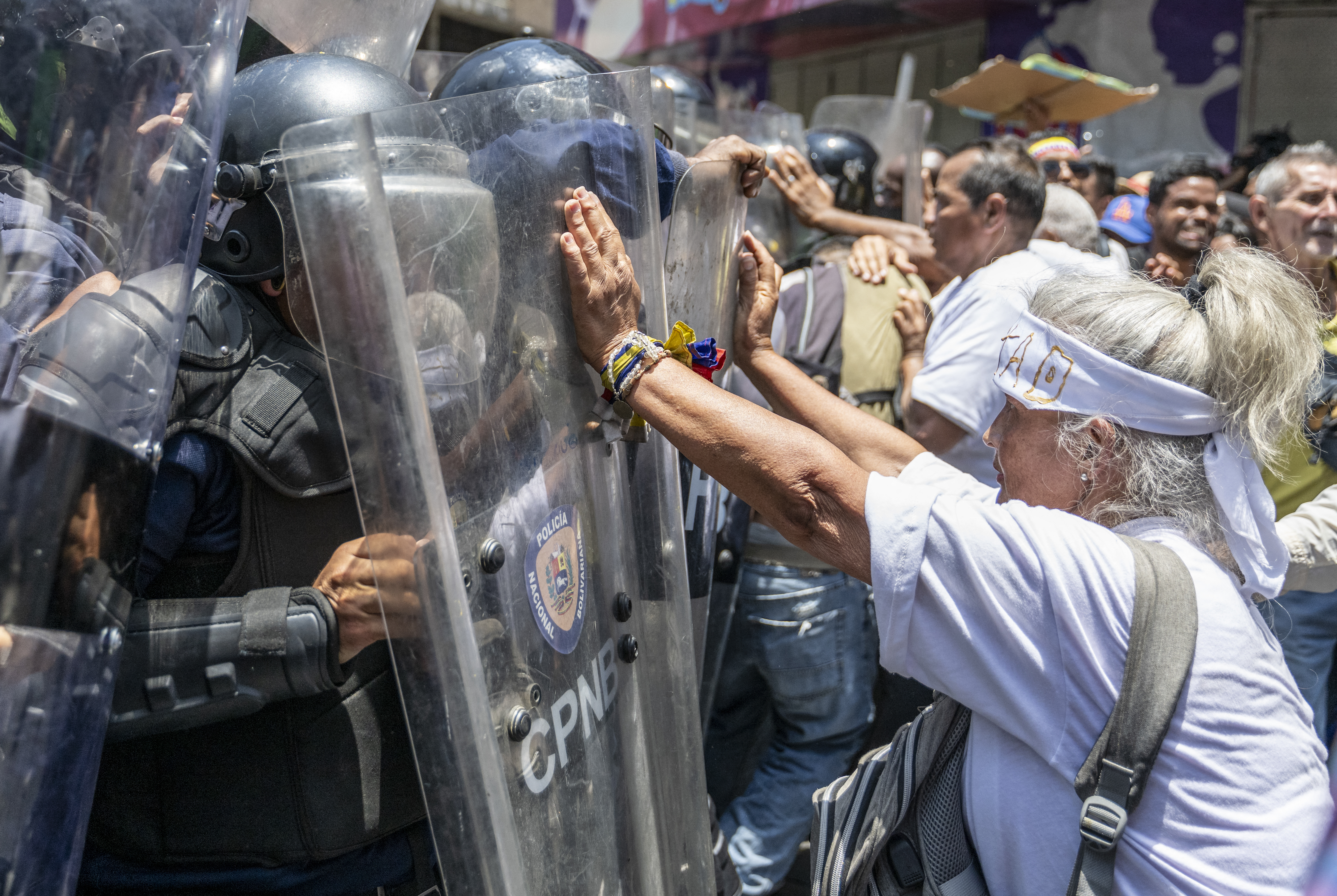 a protester places her hand on a police riot shield