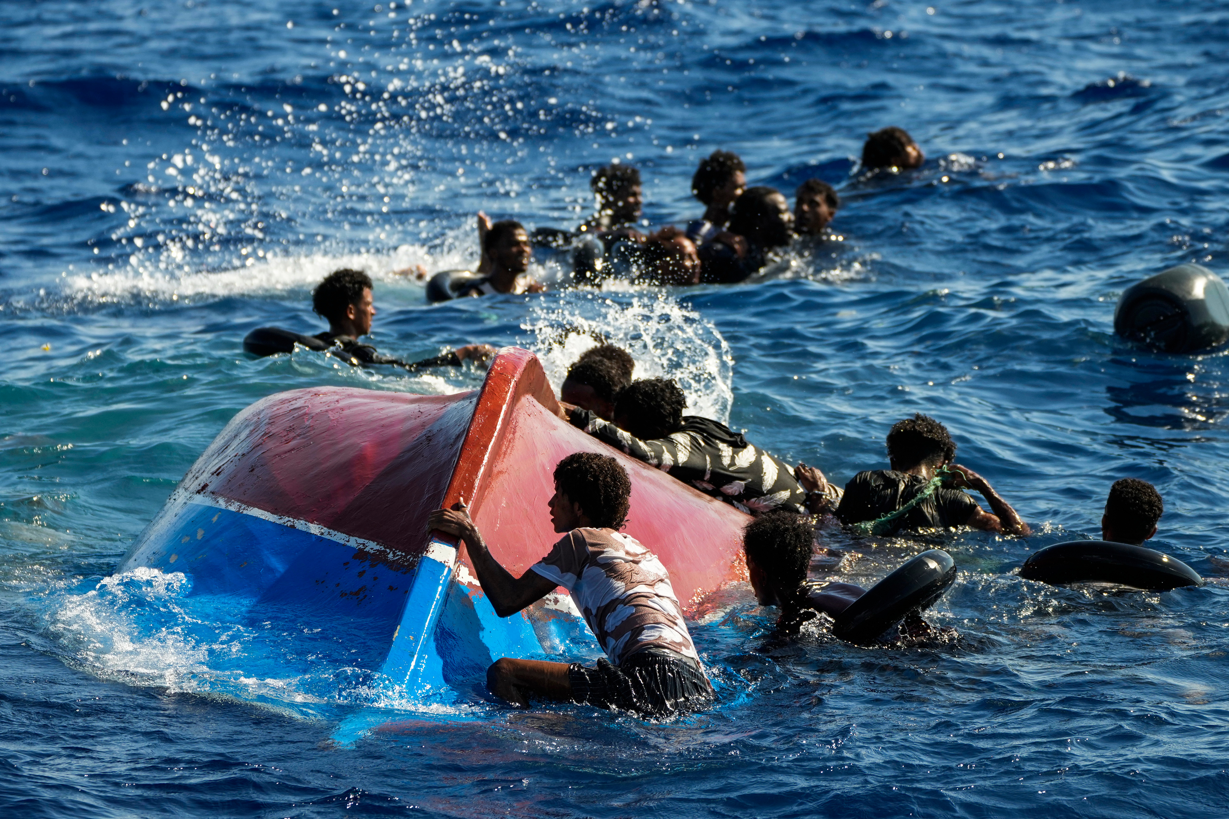 Migrants from Syria and Libya in a wooden boat call for help as they are assisted by Spanish NGO Open Arms during a rescue operation inside Malta's SAR zone south of the Italian island of Lampedusa in the Mediterranean sea on August 11, 2022.