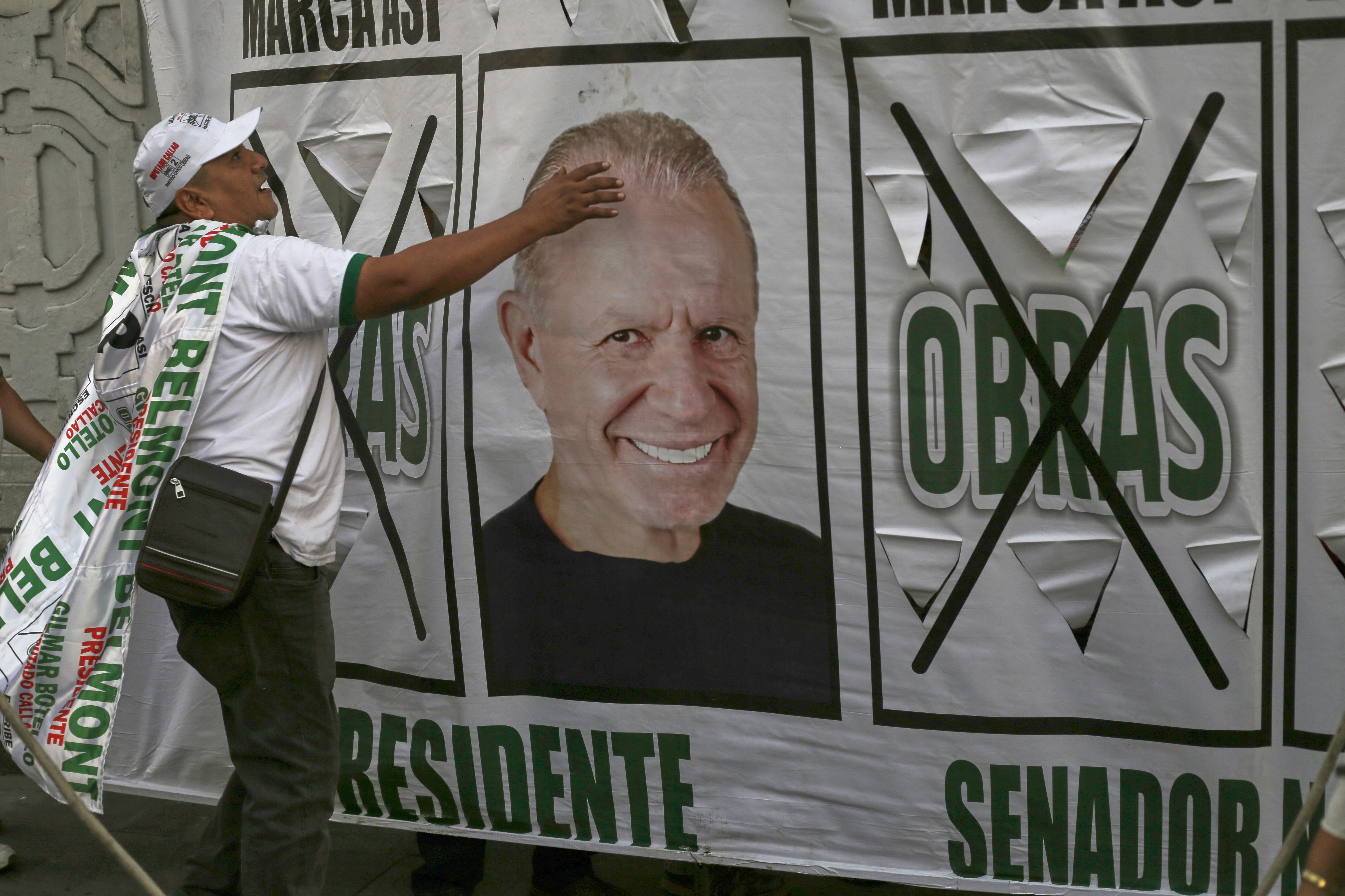 A supporter of presidential candidate Ricardo Belmont, of the Obras Civic party, touches a photo of him during a closing presidential campaign rally in Lima, Peru, Tuesday, April 7, 2026. (AP Photo/Gerardo Marin)