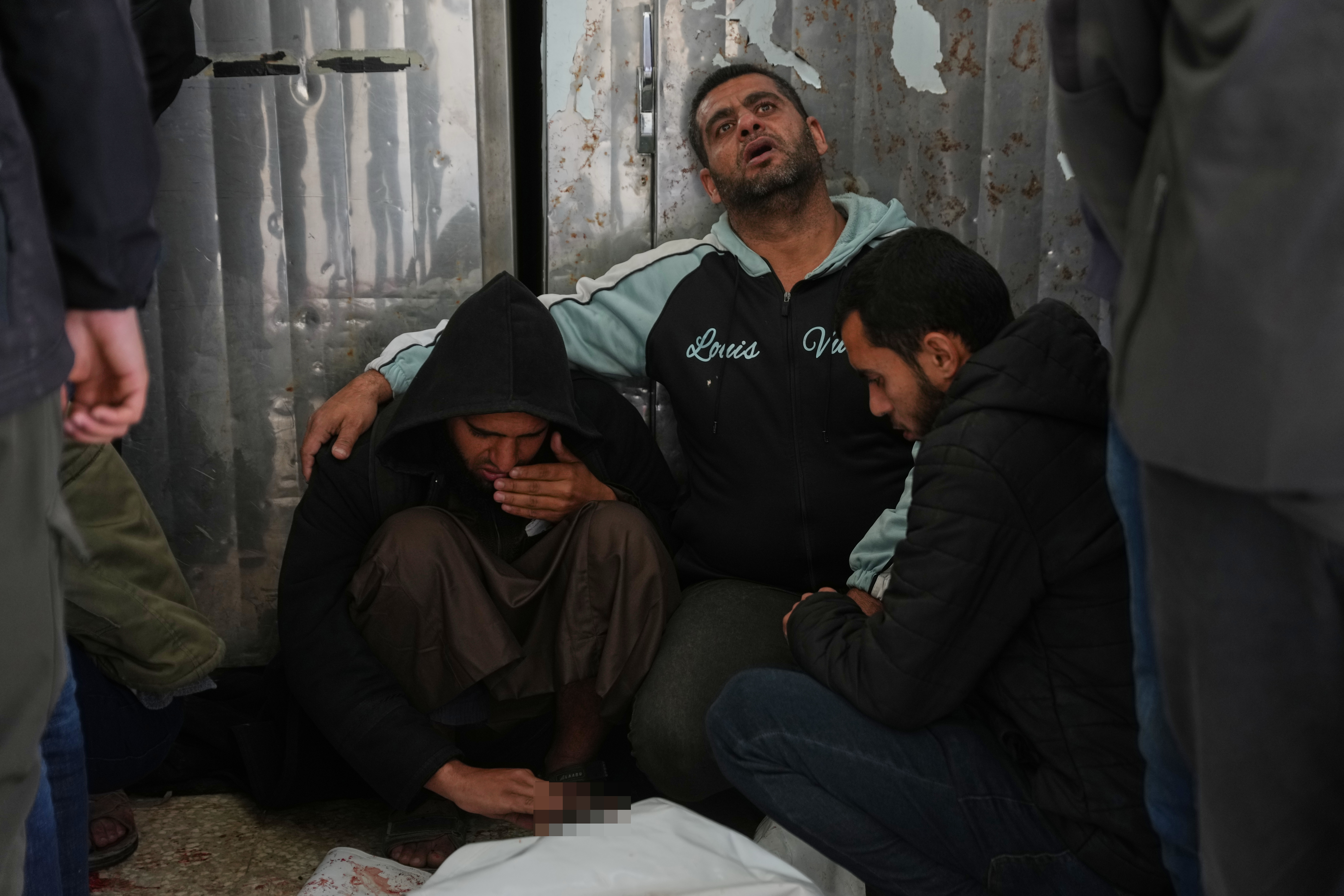 Palestinians mourn over the bodies of men killed in an Israeli strike in al-Bureij refugee camp, before their funeral at Al-Aqsa Hospital in Deir al-Balah