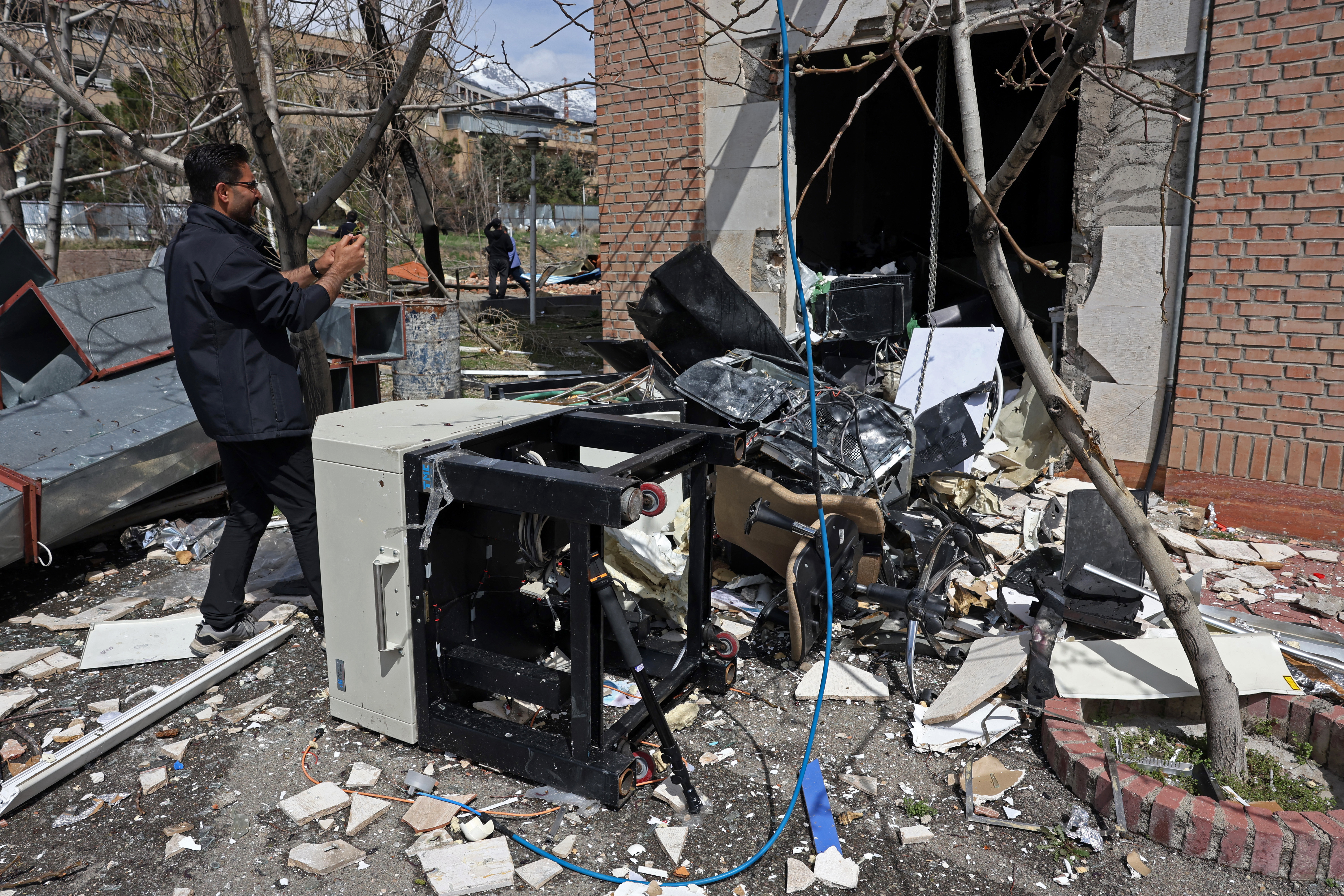 A man takes pictures of the destroyed study equipments lying amid the debris of a damaged building of the Shahid Beheshti University following a strike, in Tehran on April 4, 2026.