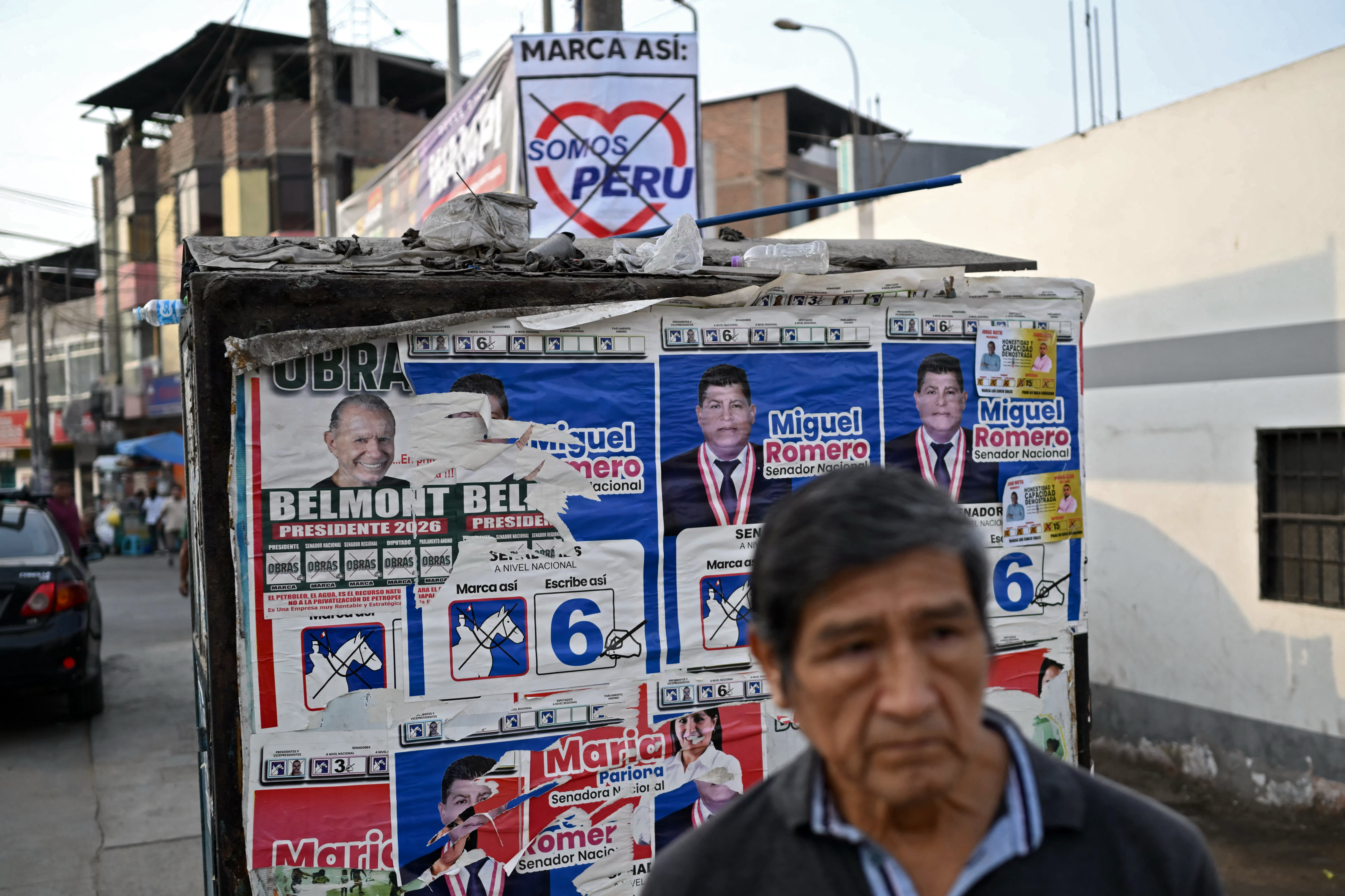 A man waits for a bus next to political propaganda in the Villa Maria del Triunfo neighborhood in Lima, on April 8, 2026.