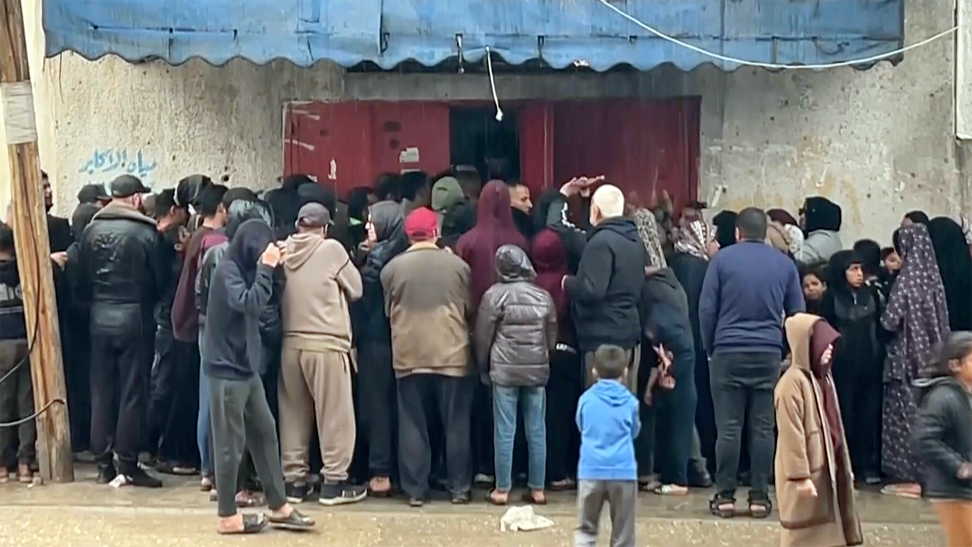 Palestinians queue for hours in pouring rain to get bread