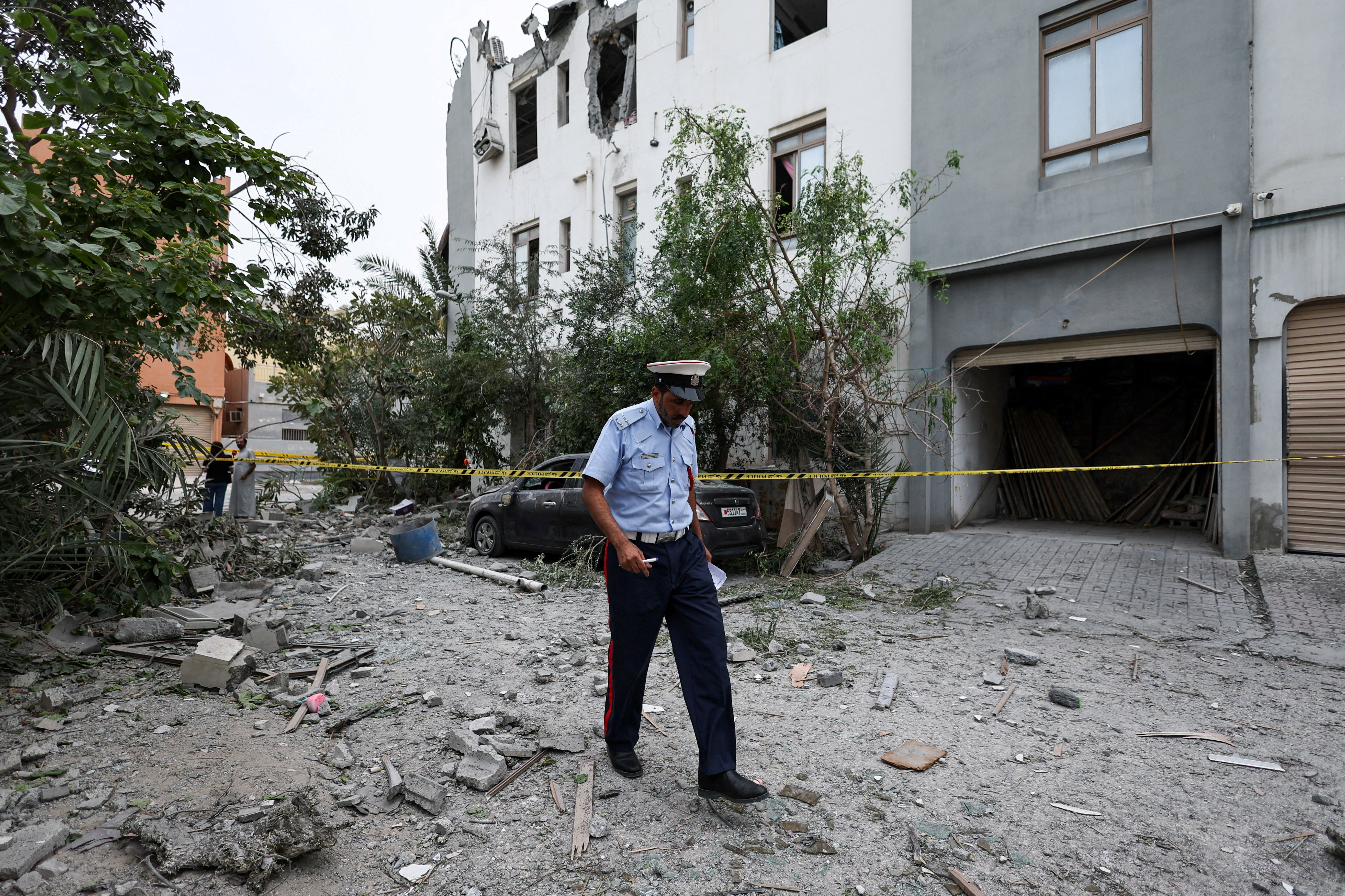 A police officer walks past a cordon tape near damaged buildings at the site of an impact of what Bahrain's Ministry of Interior (MOI) said was falling debris of an intercepted Iranian drone last night, amid the U.S.-Israeli conflict with Iran, in Sitra, Bahrain, April 4, 2026. REUTERS/Hamad I Mohammed TPX IMAGES OF THE DAY