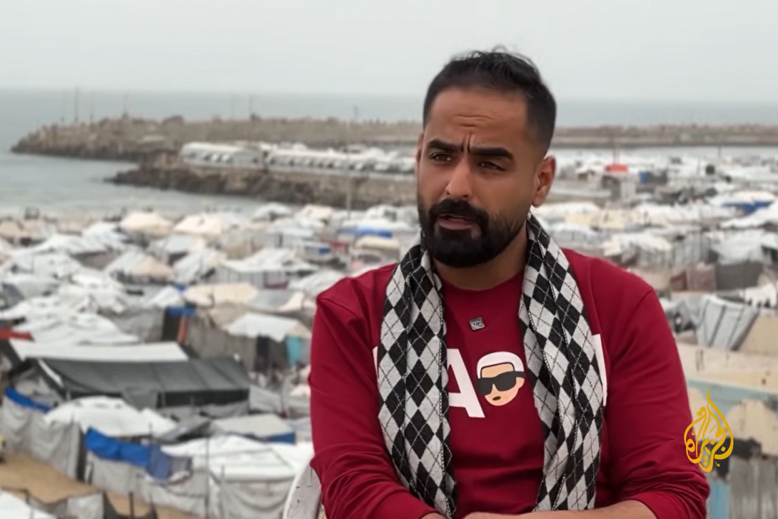 Mahmoud Shamiya, a university graduate who dreamed of becoming a teacher, now spends his days navigating a deadly routine in a displacement camp. [Screengrab/Al Jazeera]